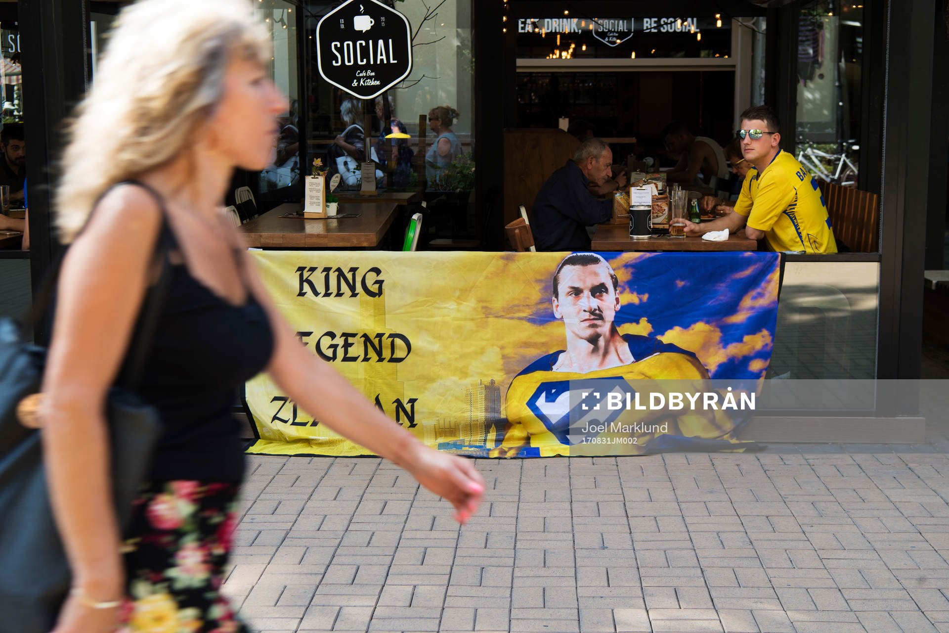 En kvinna passerar ett svenskt fan med en banderoll med en