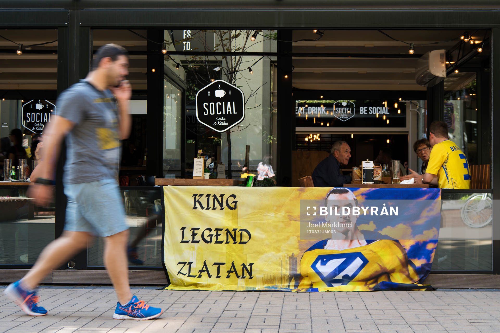 En man passerar ett svenskt fan med en banderoll med en