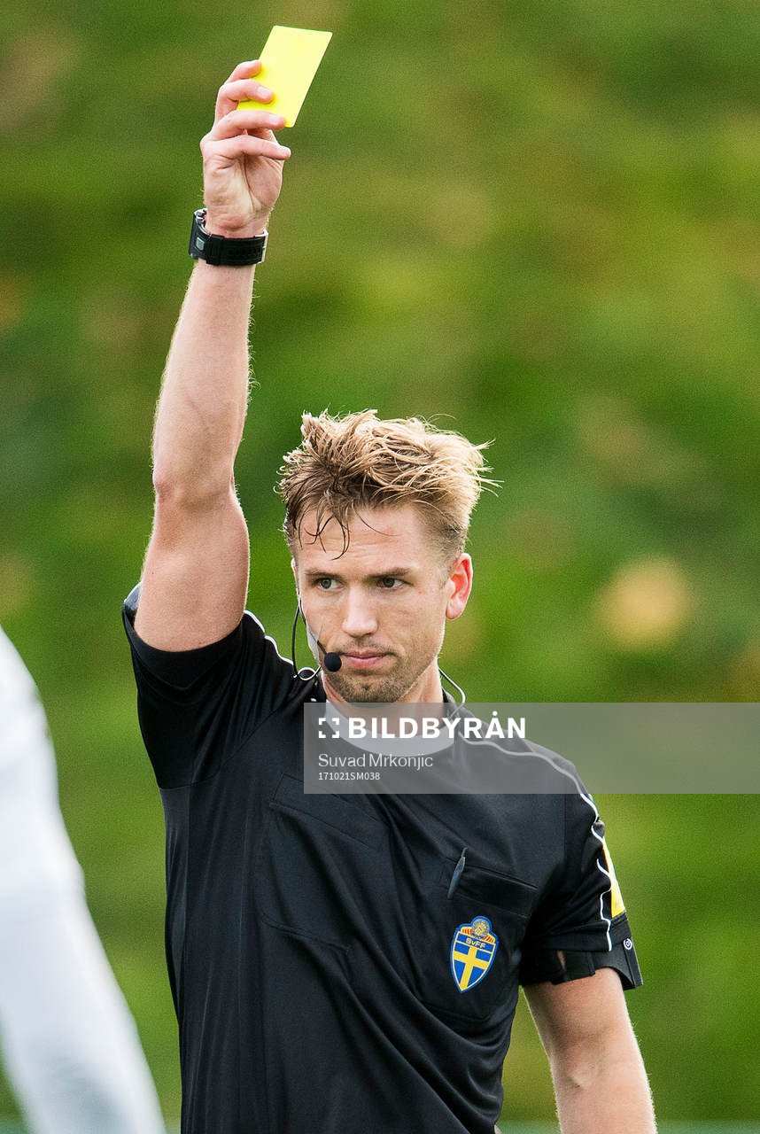 Matchens domare Fredrik Hansson visar det gula kortet