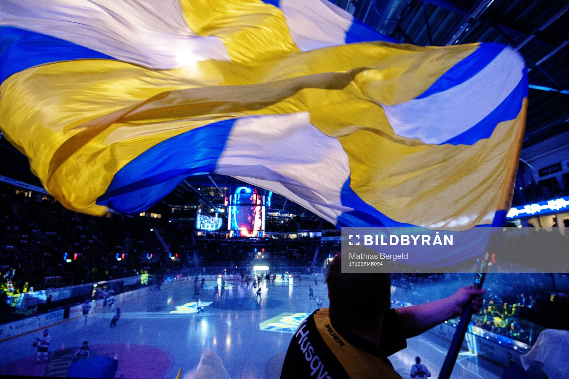 En HV71-supporter vevar med en blågul flagga