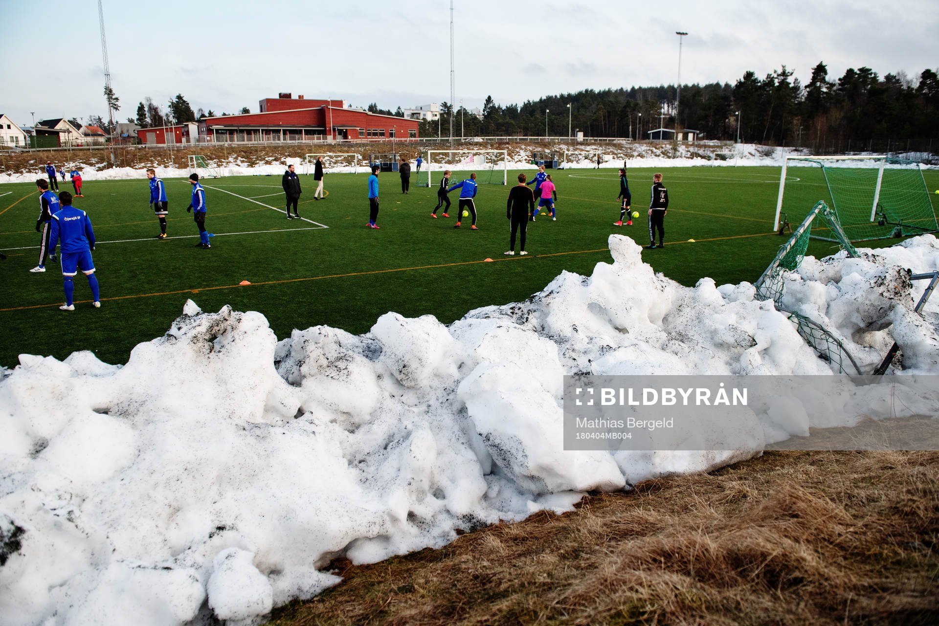 Spelarna värmer upp på plan med snövallar intill