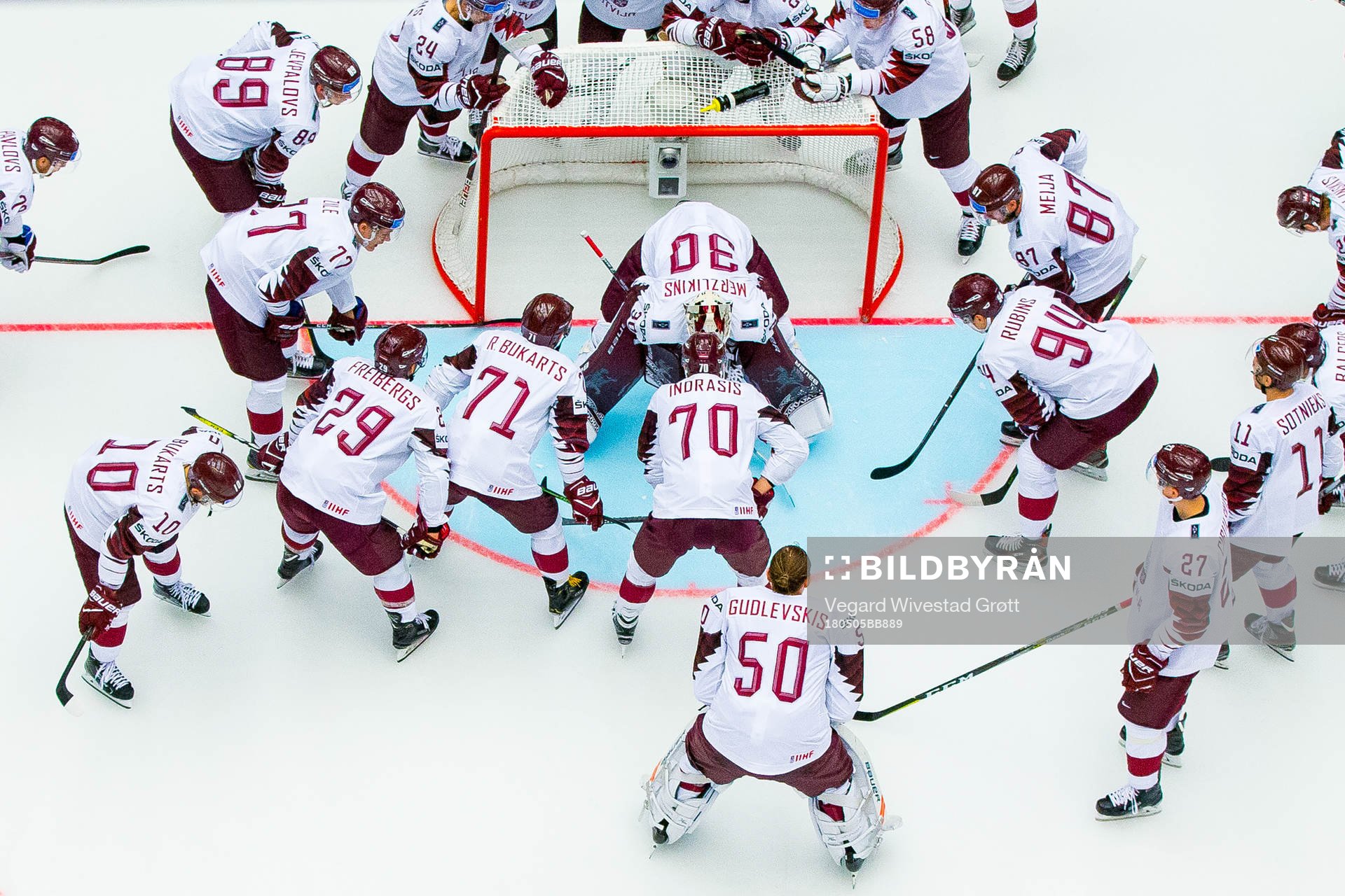 Players of Latvia gather around goaltender Elvis Merzlikins
