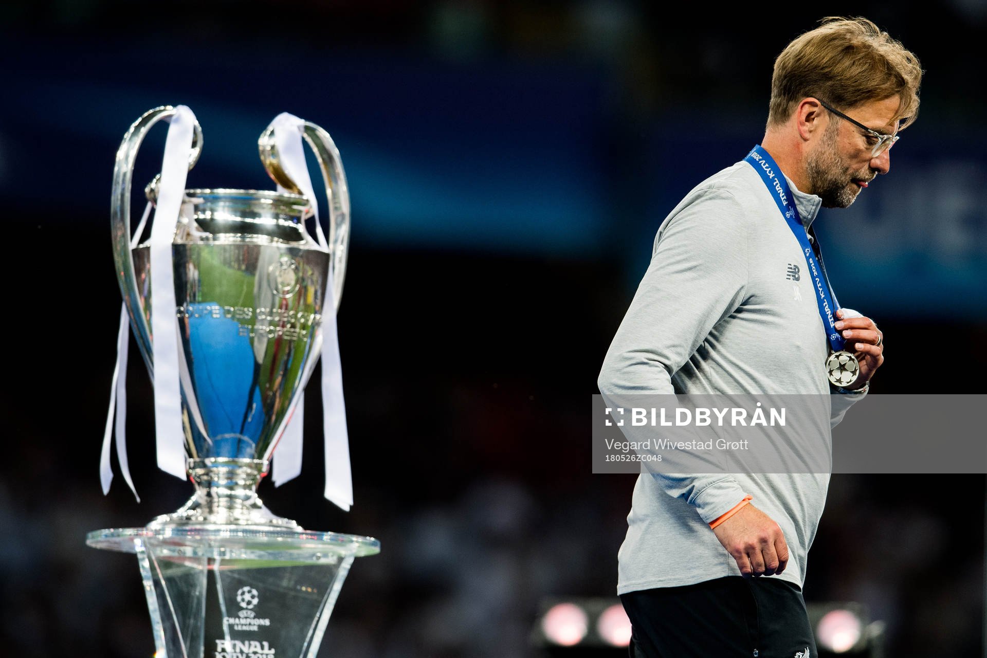 Jürgen Klopp, head coach of Liverpool, walks by the trophy