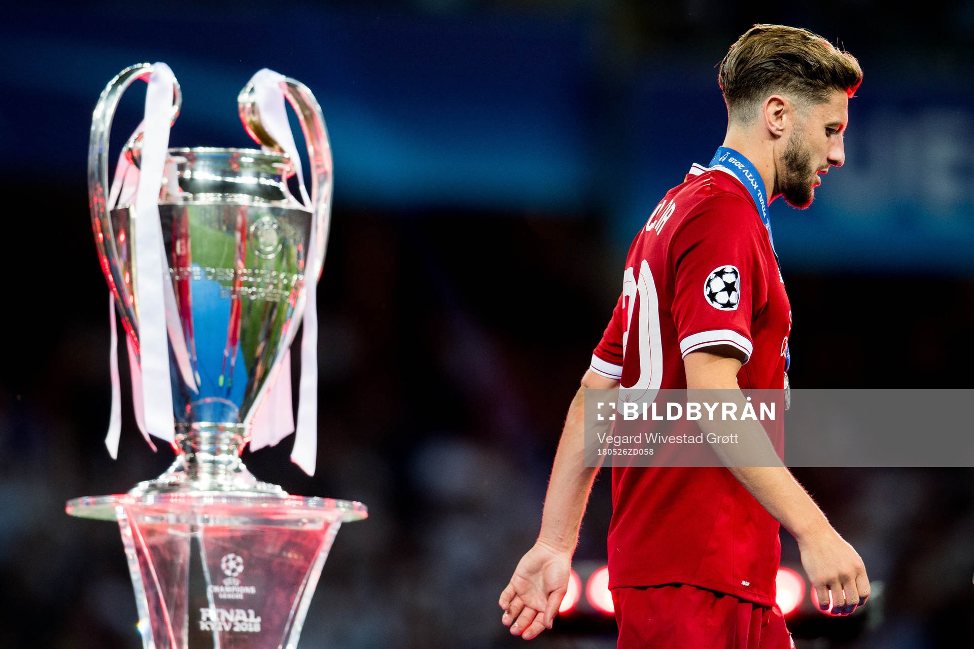 Adam Lallana of Liverpool walks dejected past the trophy