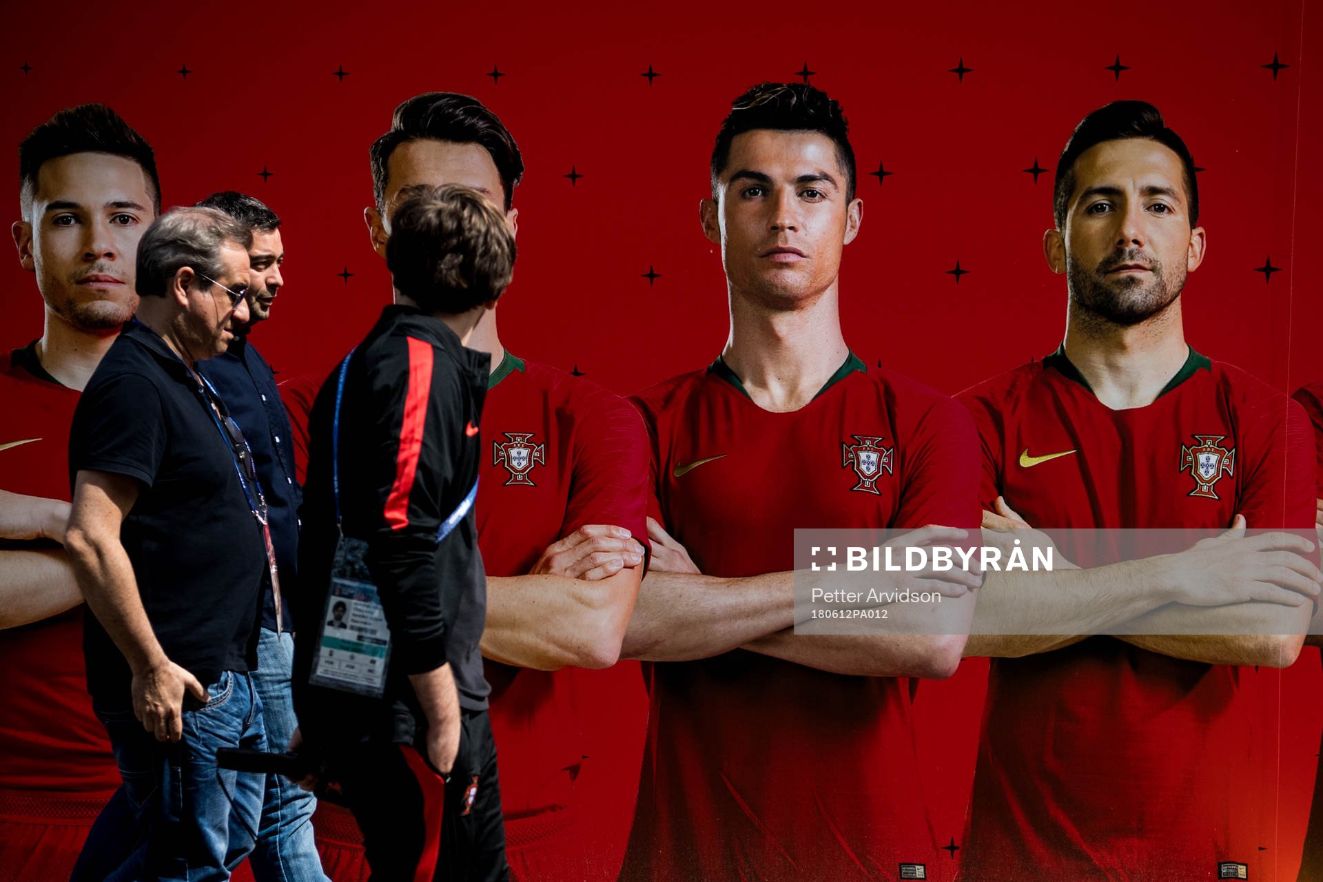 Members of the press walks by a banner with the Portuguese
