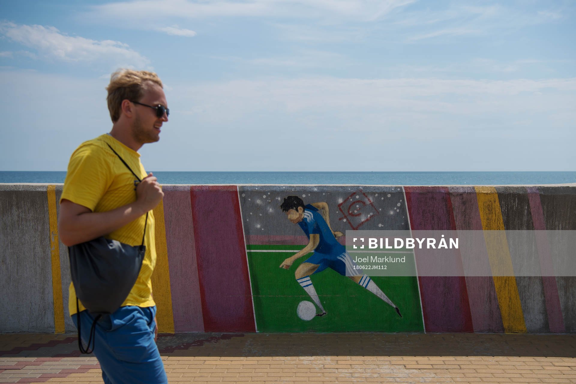 A Swedish fan passing a mural with a football player