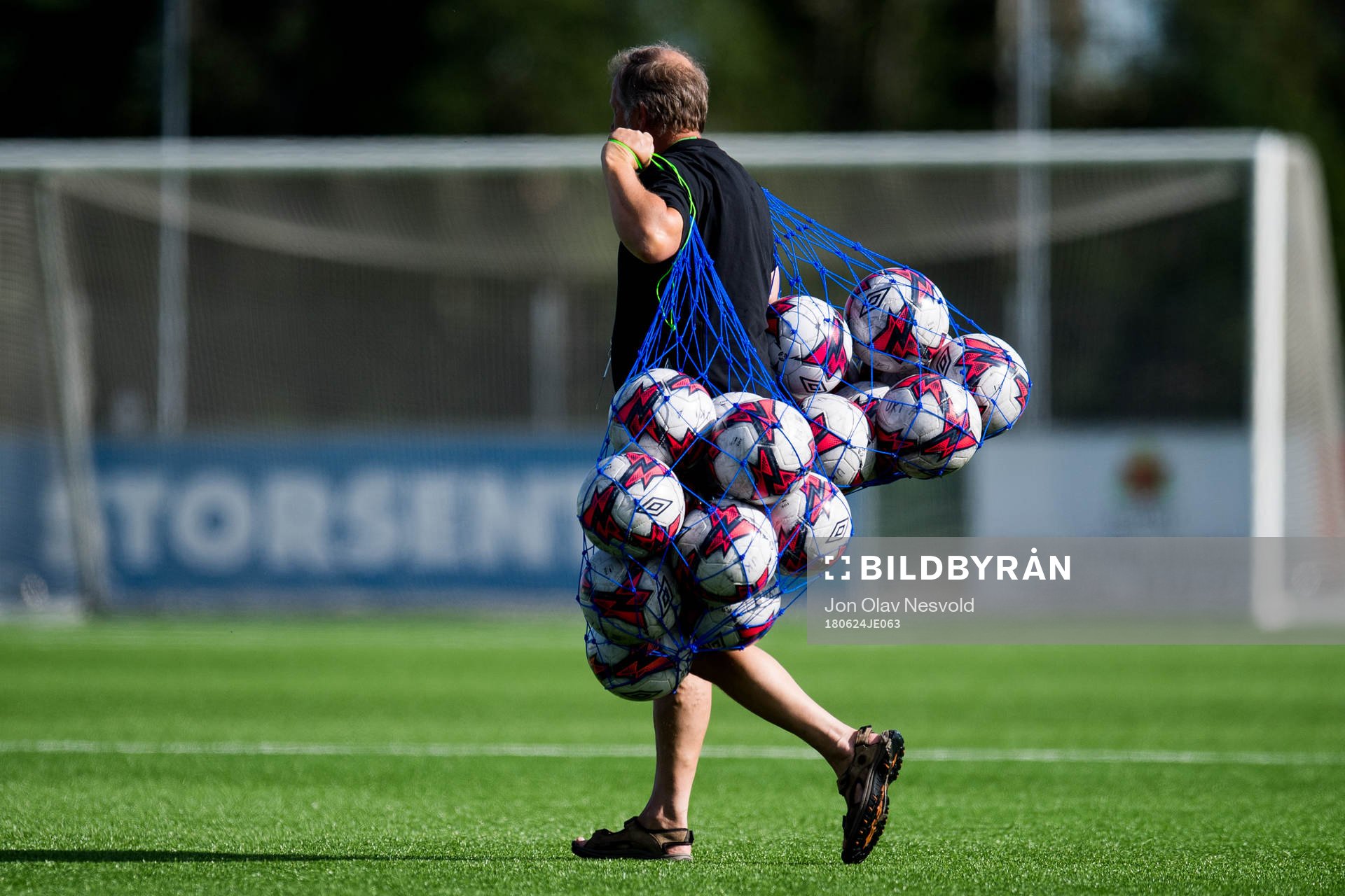A man with footballs in a net