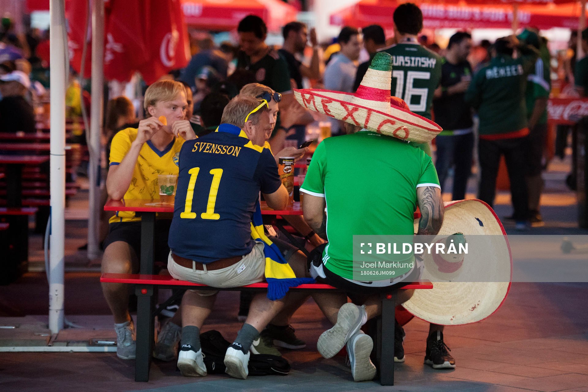 Swedish and Mexican fans sit next to each other at FIFA Fan