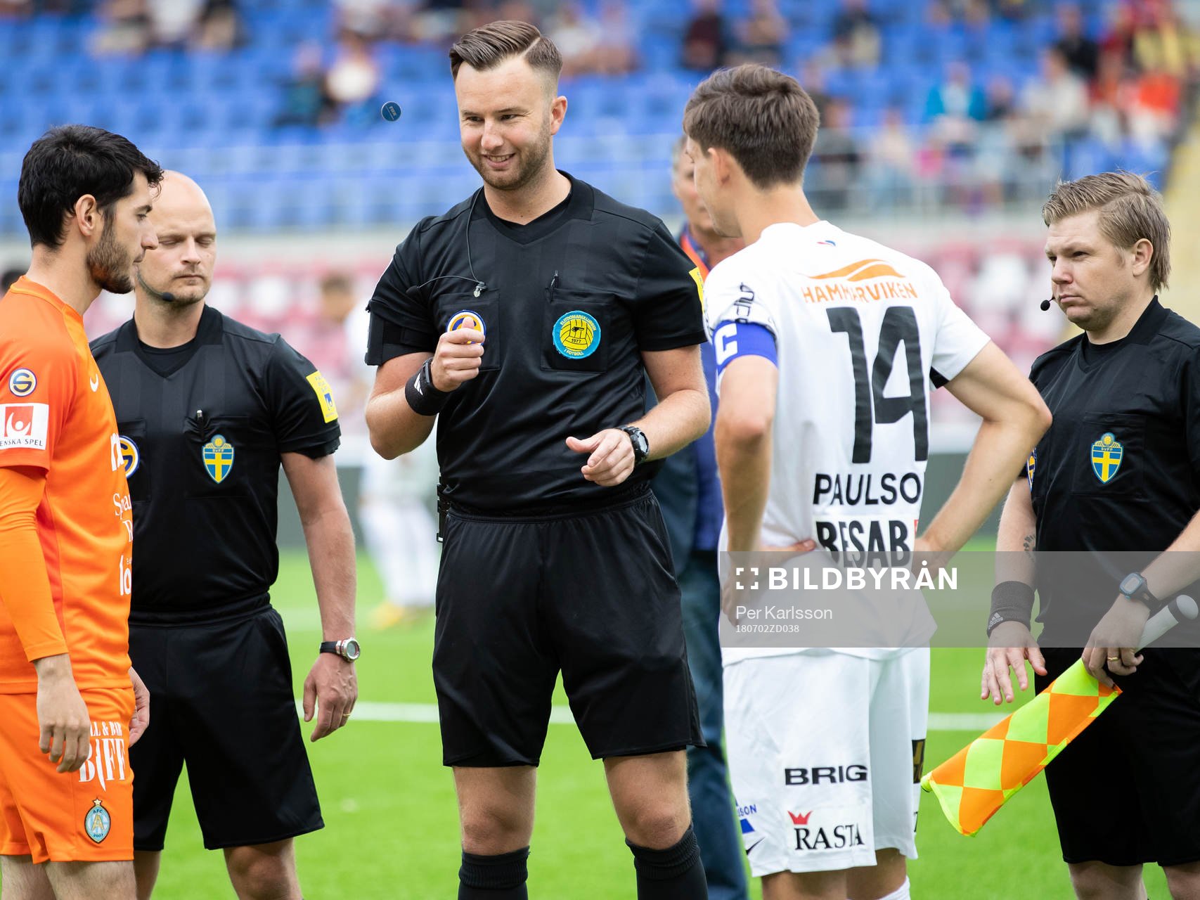 Domare Mirza Kazic singlar slant innan matchen med lagkaptenerna i AFC Eskilstunas Anel Rashkaj och Örgrytes Daniel Paulson som intresserat ser på innan fotbollsmatchen i Superettan mellan AFC Eskilstuna och Örgryte den 2 juli i Eskilstuna.