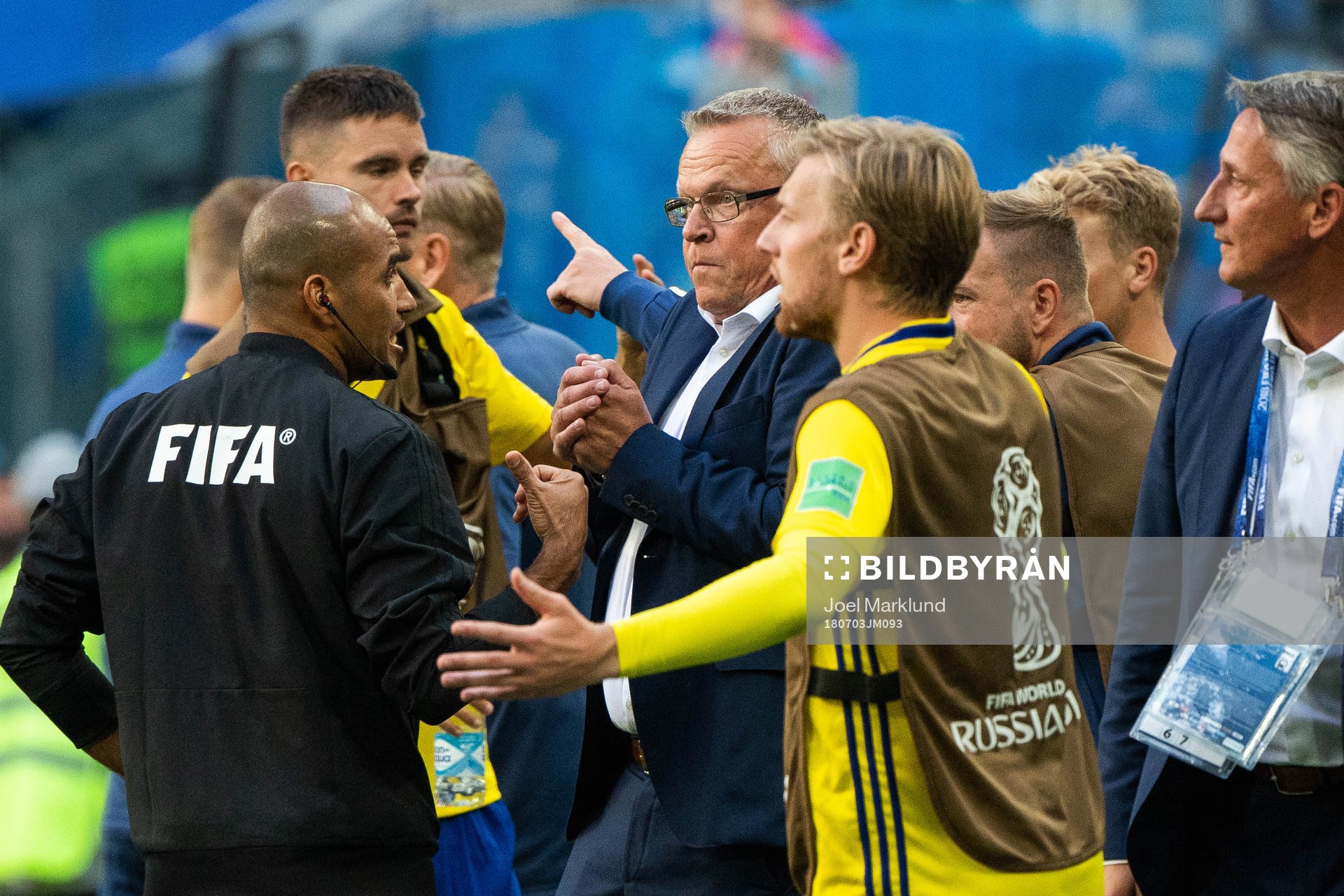 A referee talks with head coach Janne Andersson of Sweden
