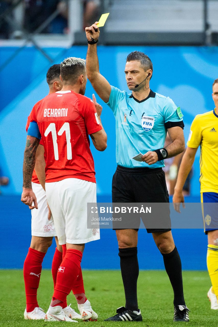 Referee Damir Skomina gives Valon Behrami a yellow card