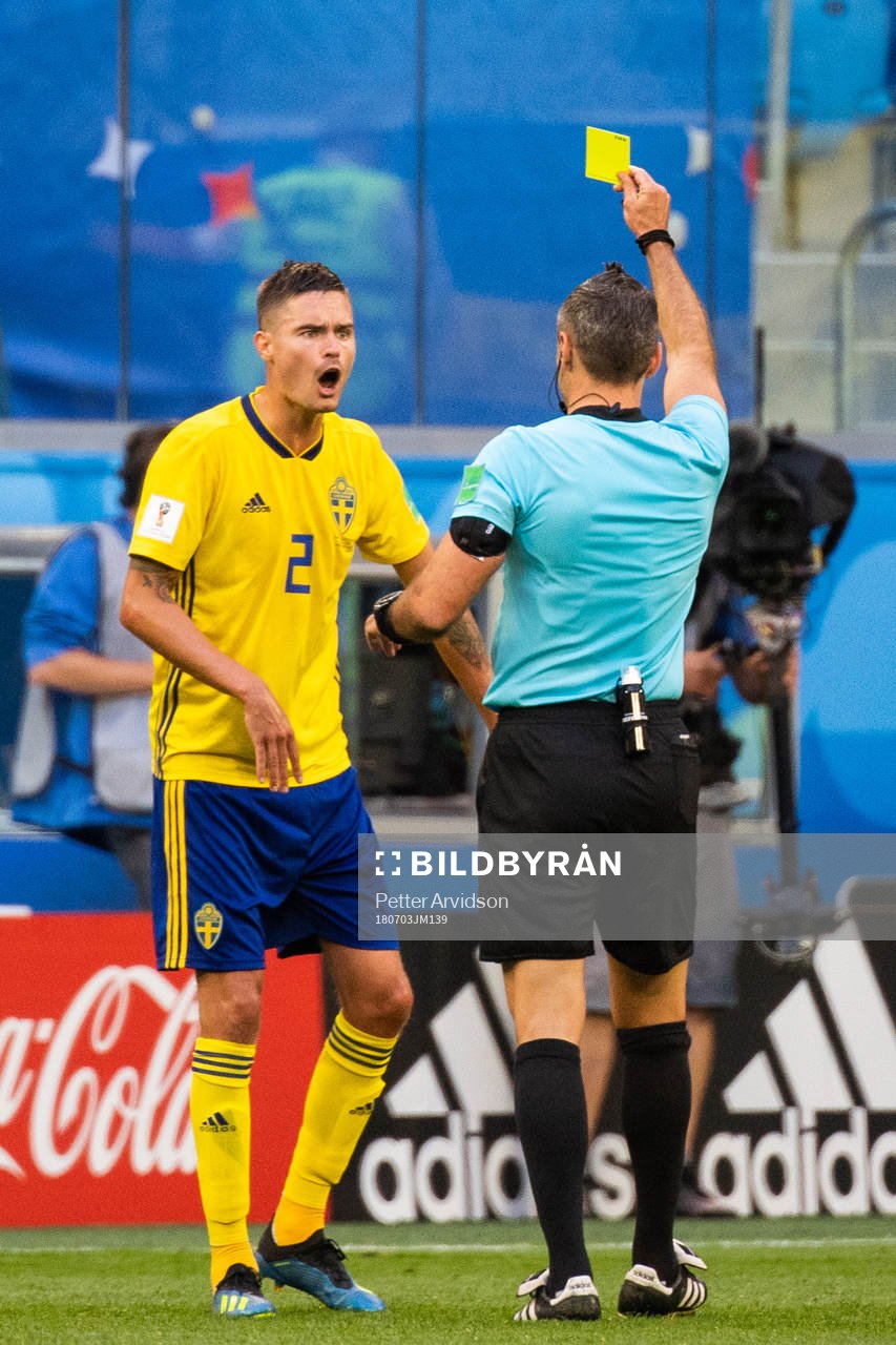 Mikael Lustig of Sweden is given a yellow card by referee