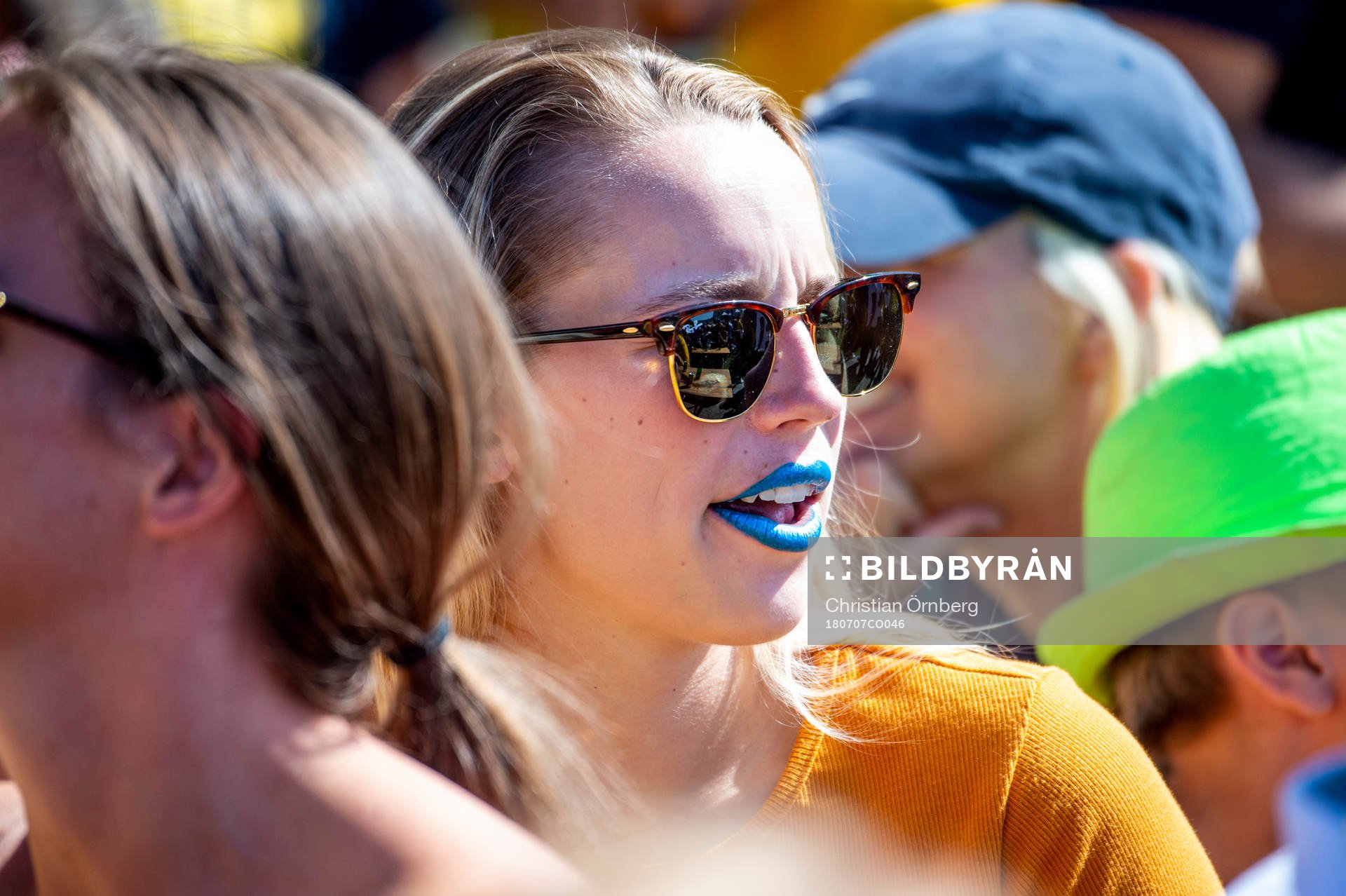 Kvinnlig supporter med blått läppstift följer matchen