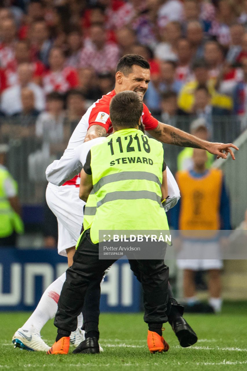 Dejan Lovren of Croatia and a steward hold a pitch invader during the FIFA World Cup final match between France and Croatia on July 15, 2018 in Moscow.