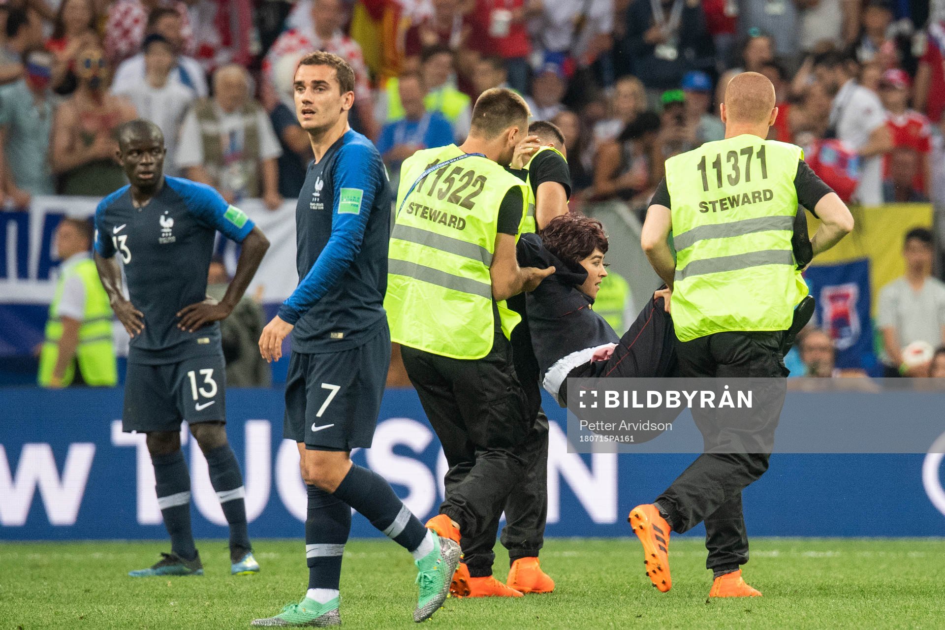 Stewards carry away a pitch invader