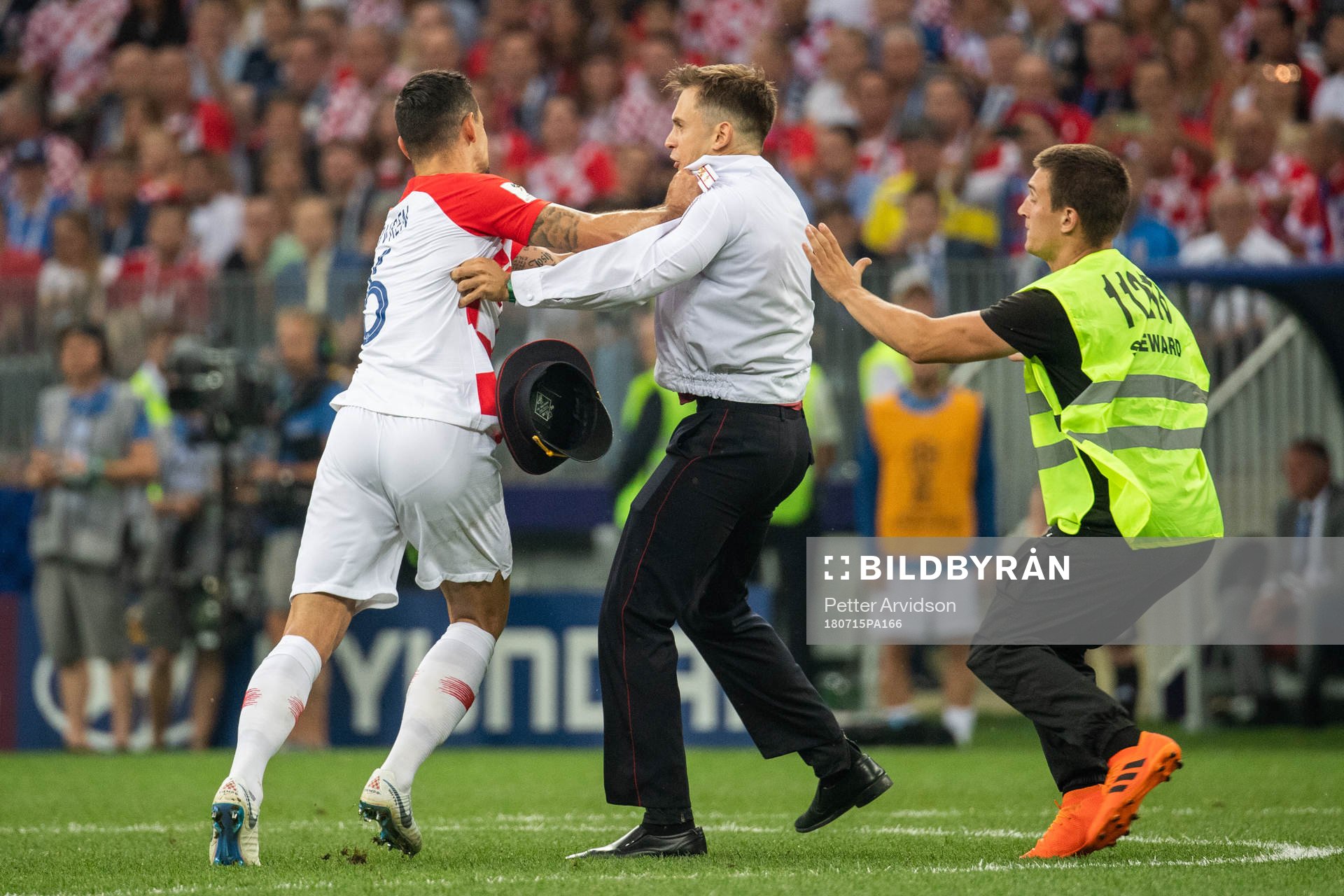 Dejan Lovren of Croatia and a stewards in a situation with a pitch invader during the FIFA World Cup final match between France and Croatia on July 15, 2018 in Moscow.