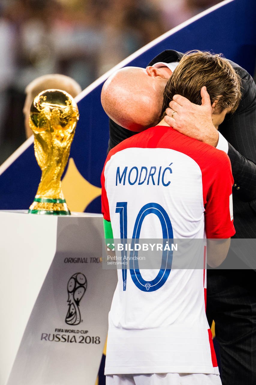 Luka Modric of Croatia walks by the trophy and gets a hug
