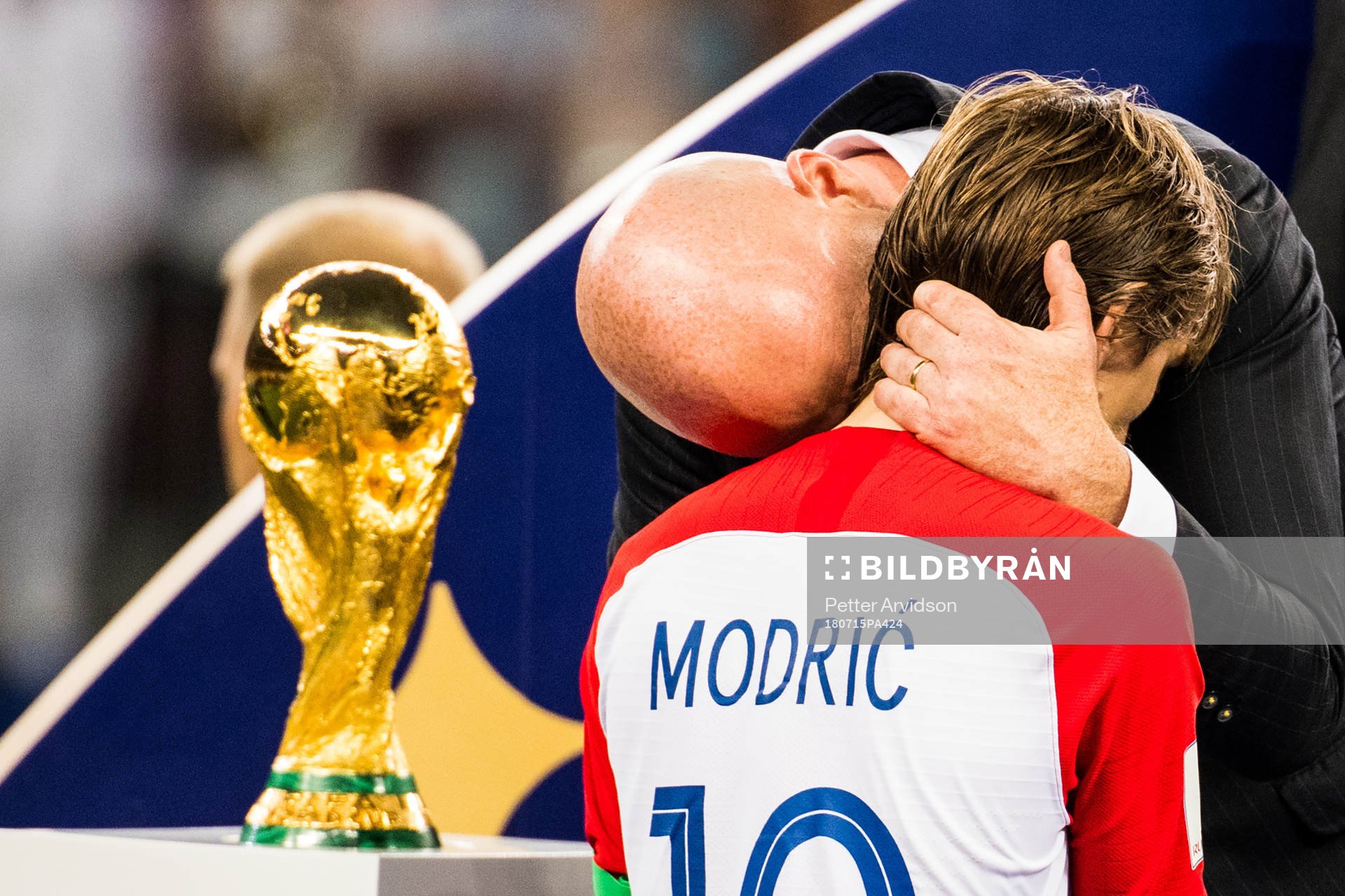 Luka Modric of Croatia walks by the trophy and gets a hug