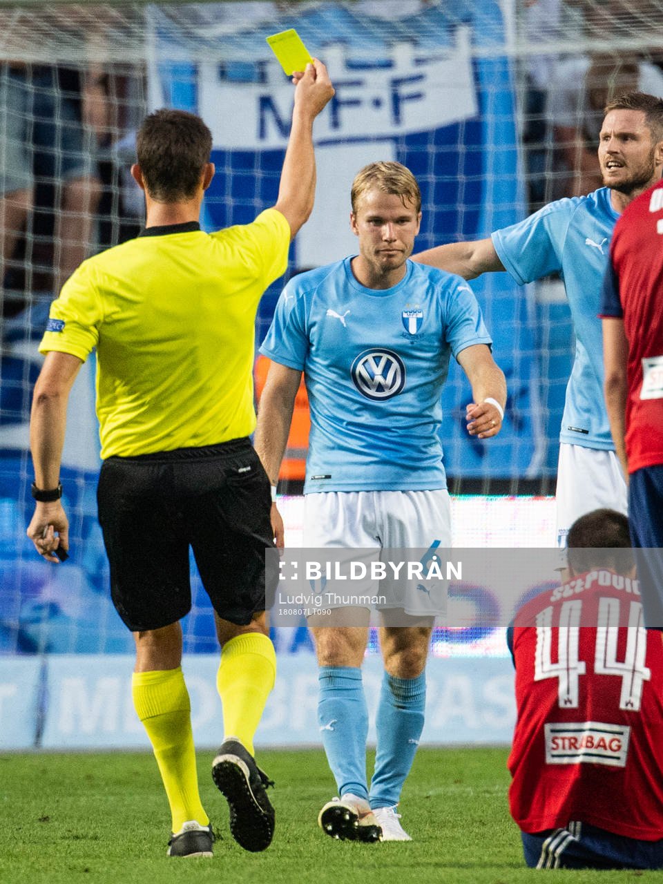 Referee Matej Jug gives a yellow card to Oscar Lewicki of