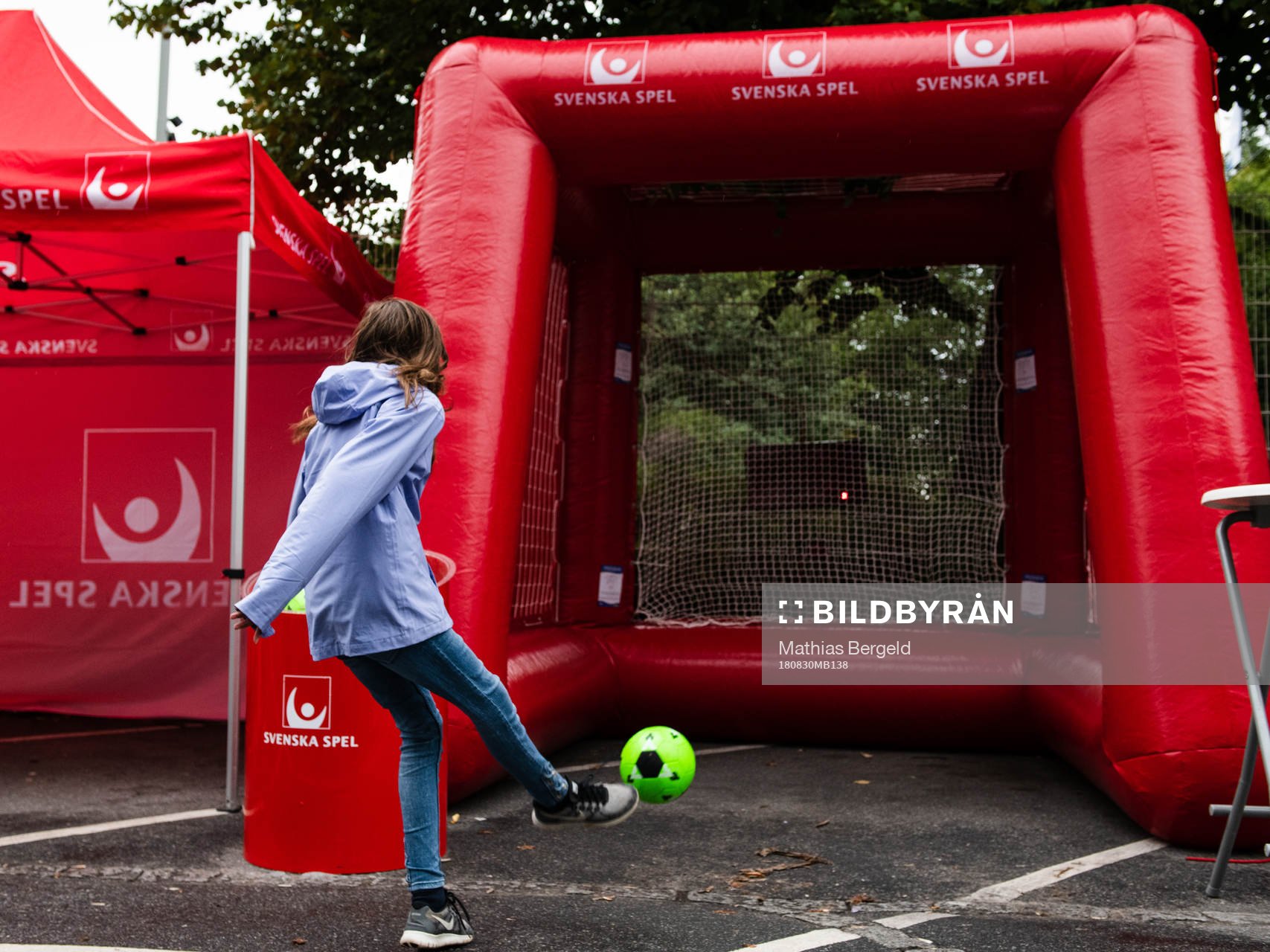 En tjej skjuter en fotboll i Svenska Spels monter i fanzone