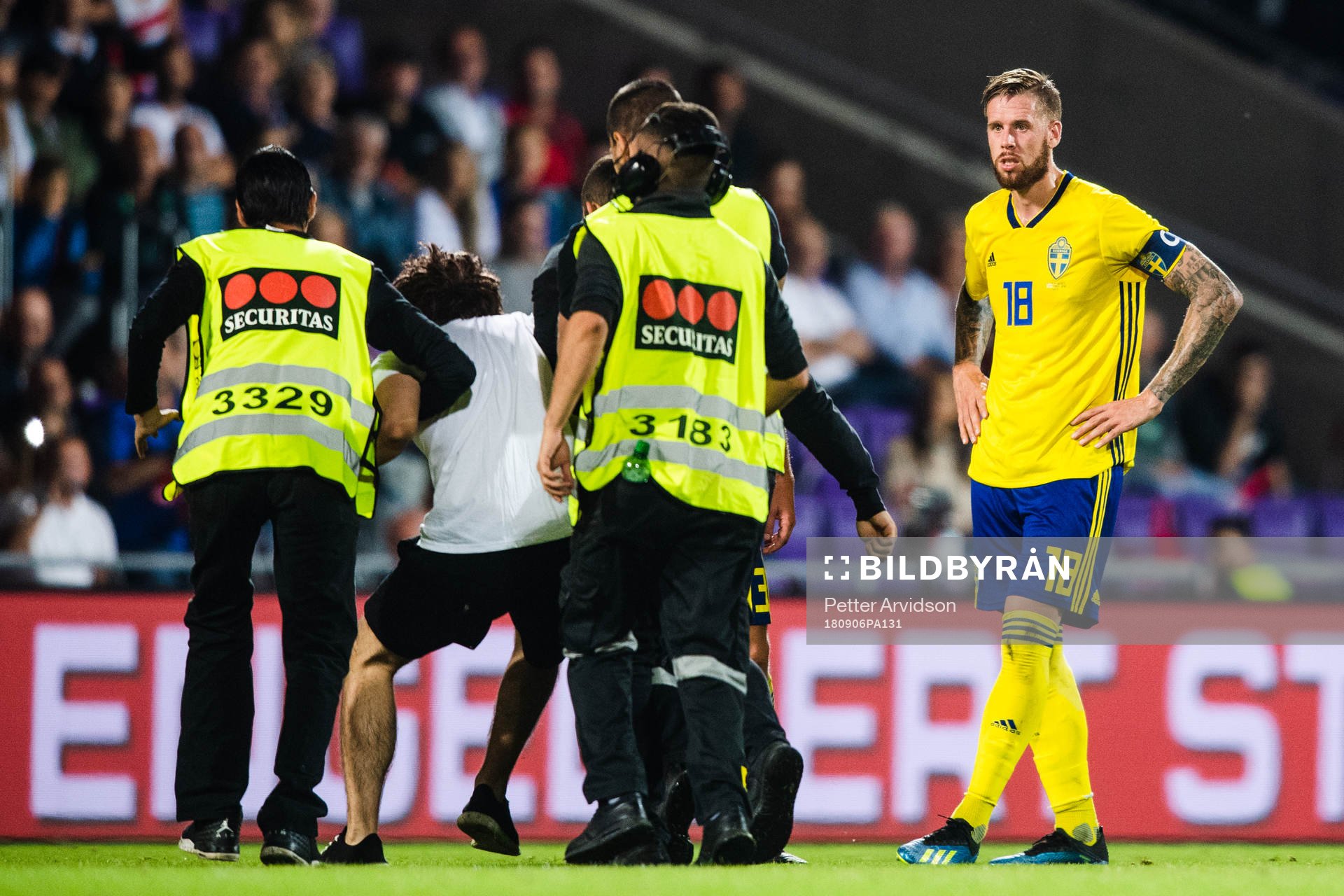 Pontus Jansson of Sweden sees a pitch invader escorted by