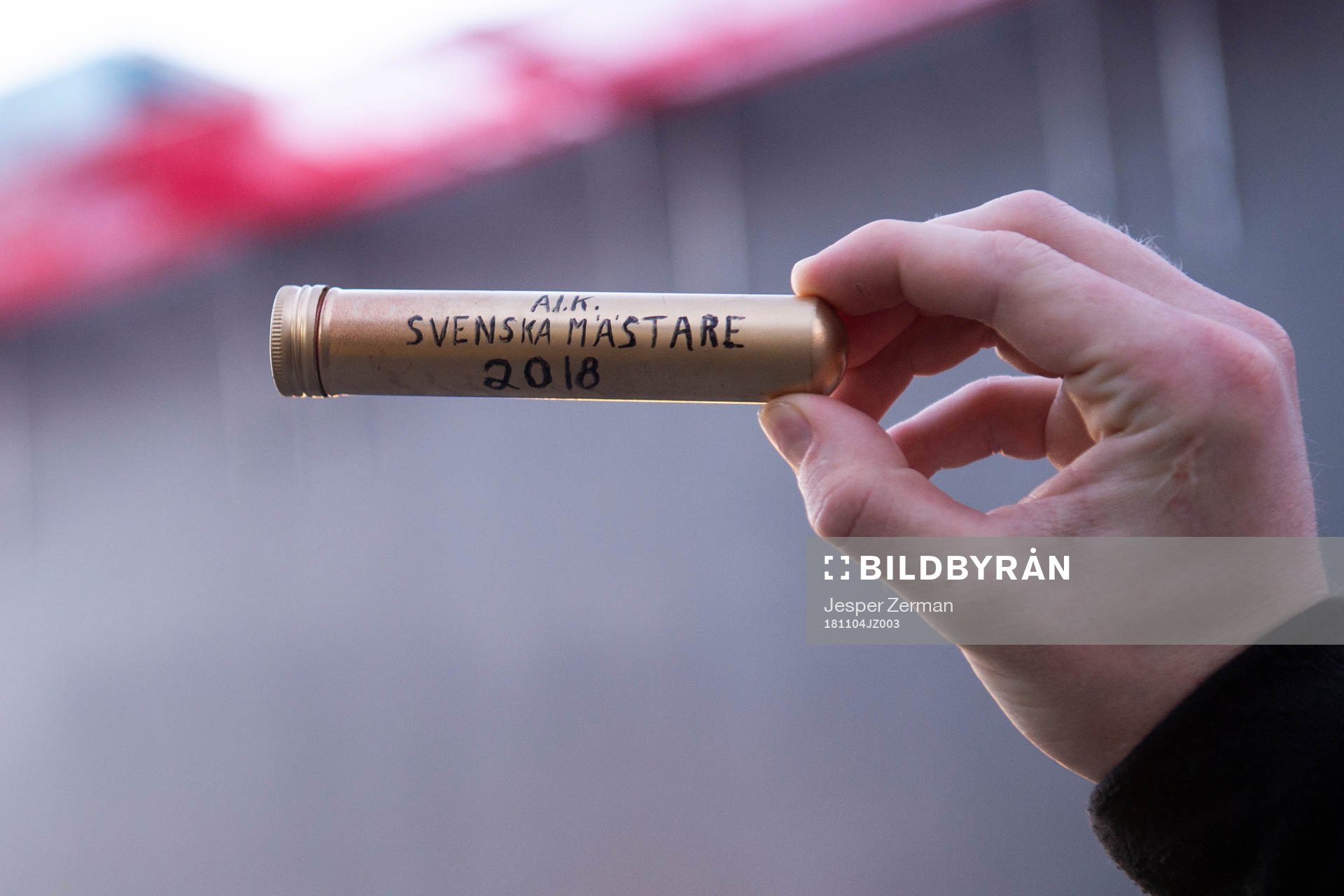 En AIK-supporter håller upp en cigarr
