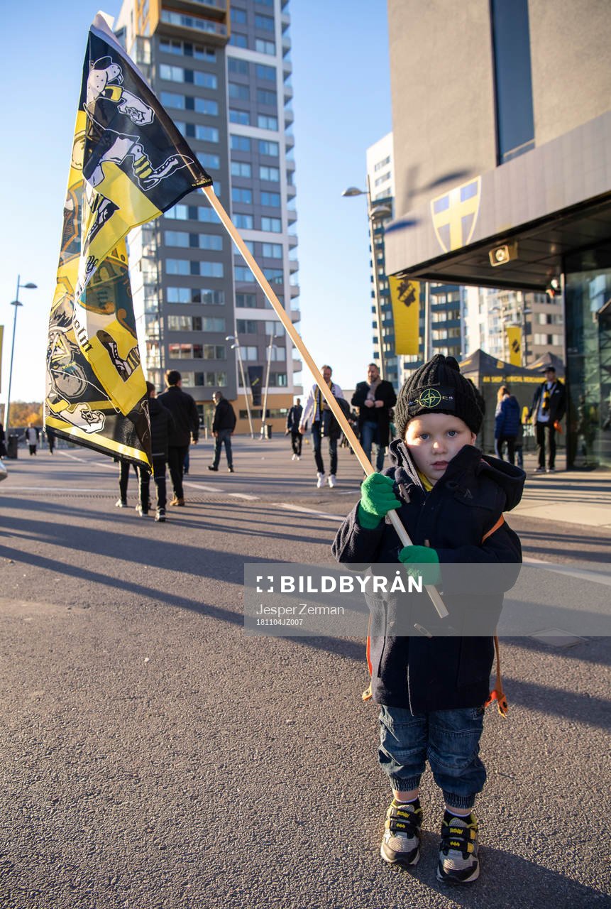 En ung AIK-supporter håller upp en flagga