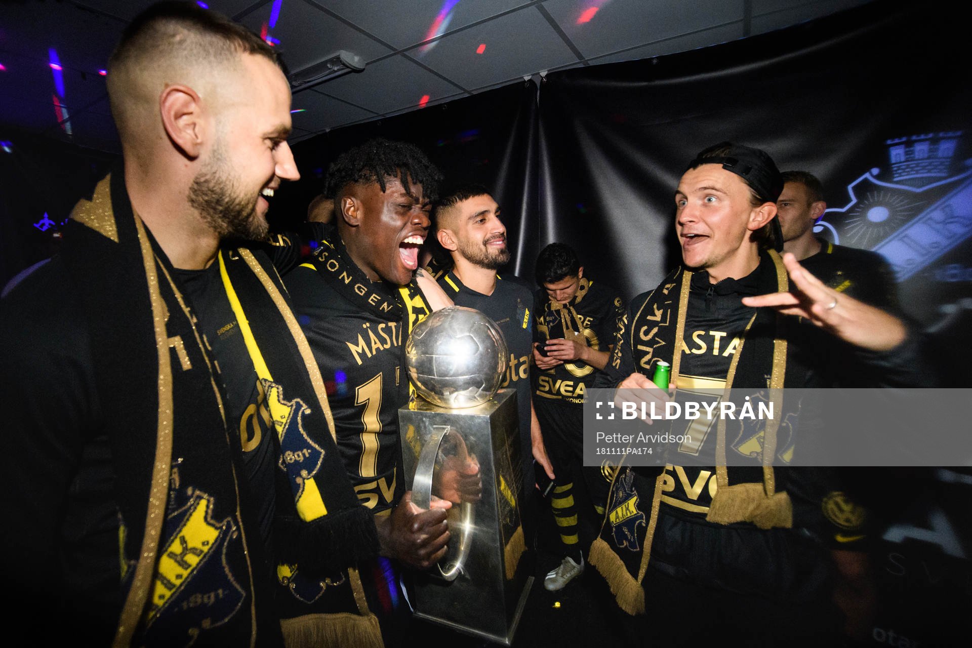 AIK:s Alexander Milosevic, Daniel Mushitu och Kristoffer Olsson jublar med Lennart Johanssons pokal i omklädningsrummet efter att AIK blivit Svenska Mästare efter fotbollsmatchen i Allsvenskan mellan Kalmar och AIK den 11 november 2018 i Kalmar.