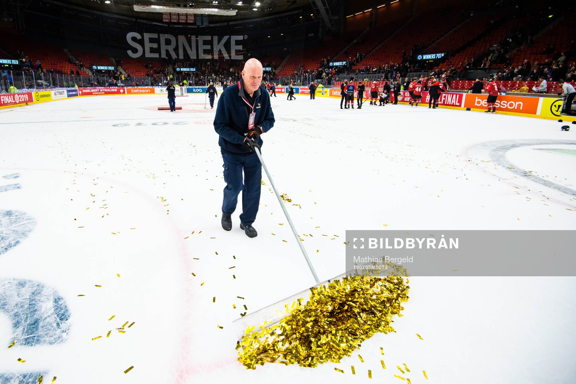 A janitor scrapes gold glitter of the ice