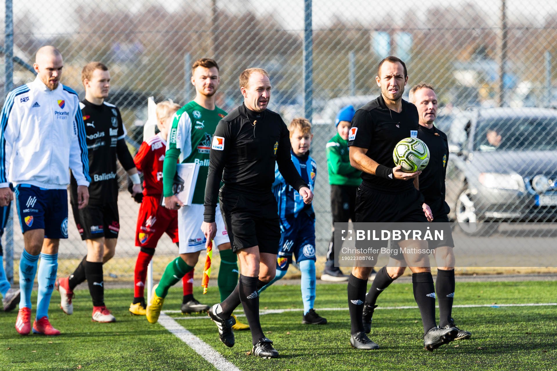 Båda lagens spelare gör entré till fotbollsmatchen i