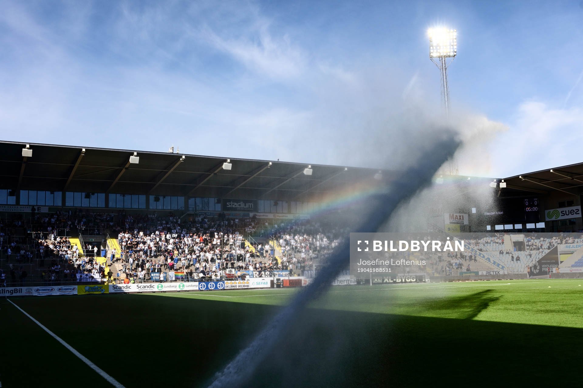 Vattning av konstgräset ger regnbågen framför Curva