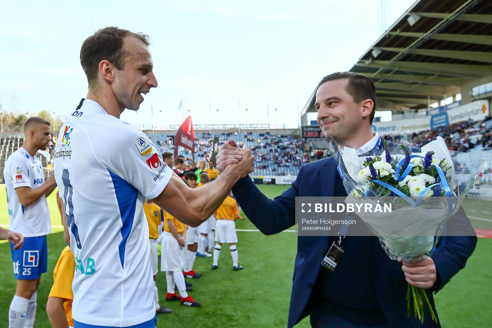 IFK Norrköpings Lars Krogh Gerson efter 100 allsvenska matcher, gratuleras av klubbdirektör Jens Magnusson under fotbollsmatchen i Allsvenskan mellan IFK Norrköping och Falkenberg den 19 april 2019 i Norrköping.