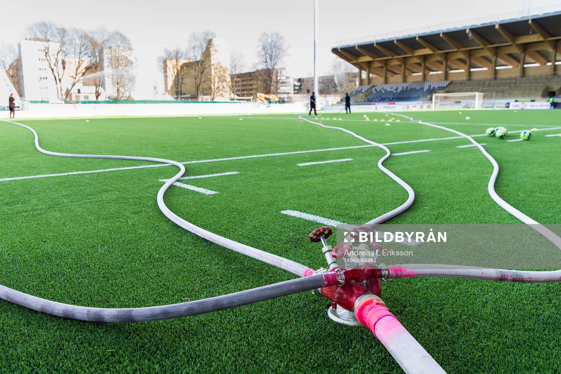 Planen vattnas för hand innan fotbollsmatchen i