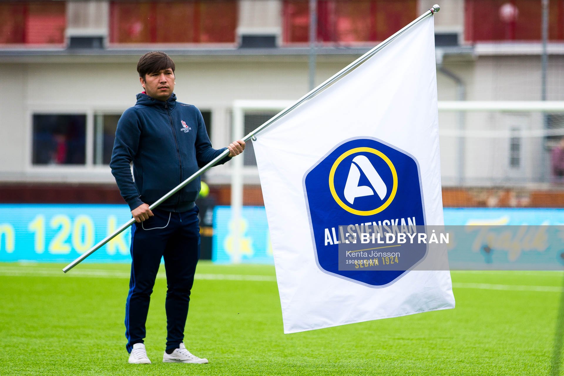 En funktionär med en flagga med Allsvenskans logotyp
