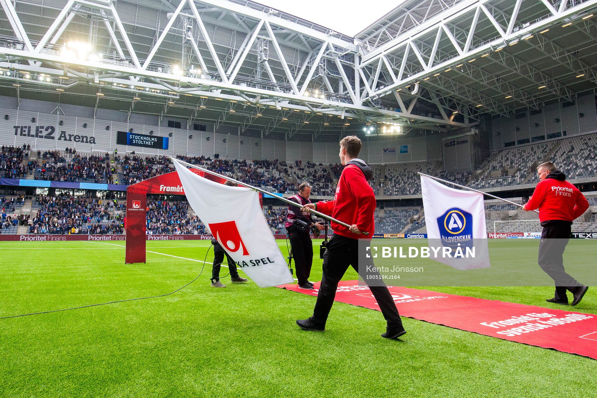 Funktionärer med flaggor med Svenska Spels och