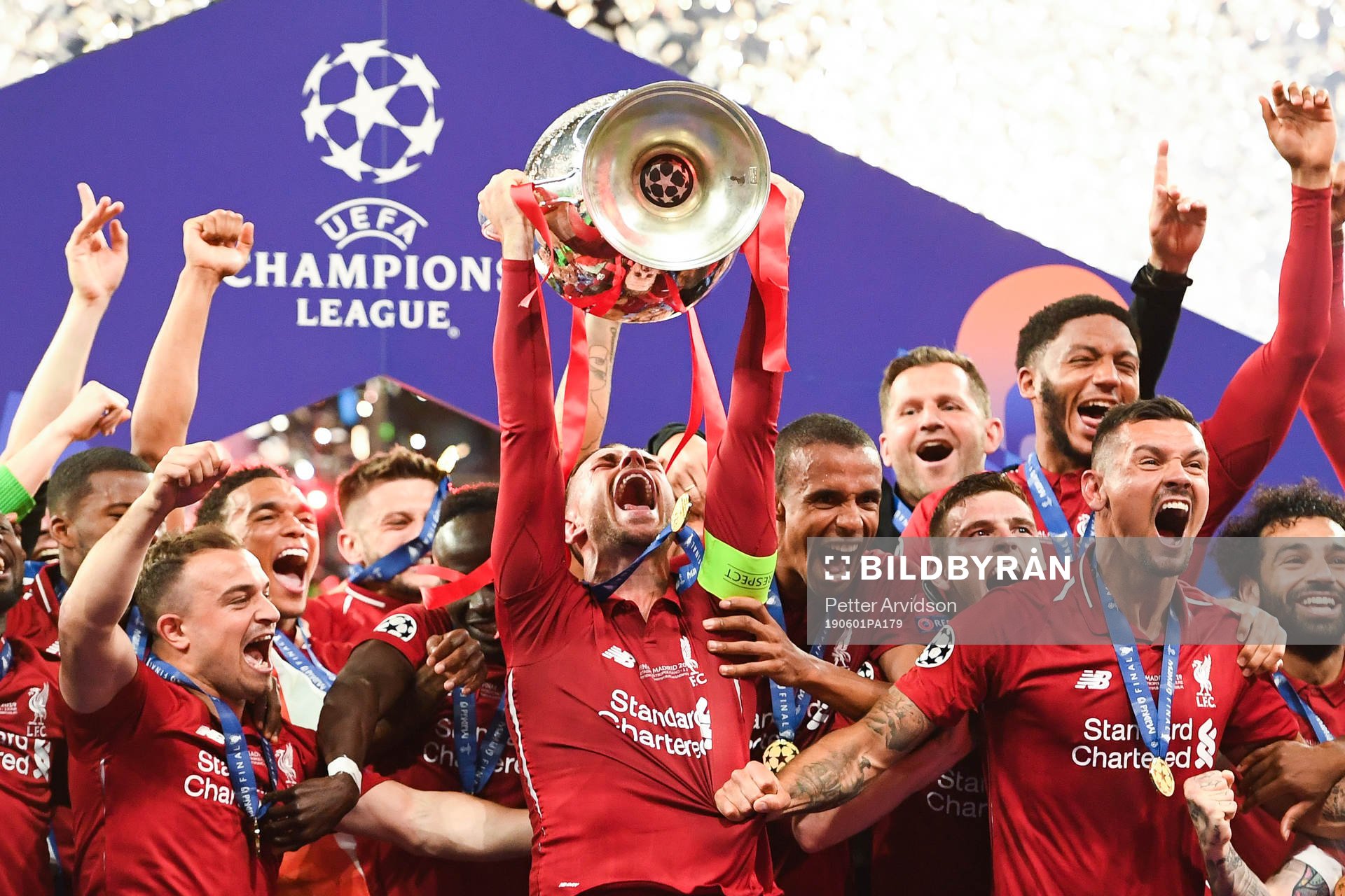 Jordan Henderson of Liverpool raises the throphy in front