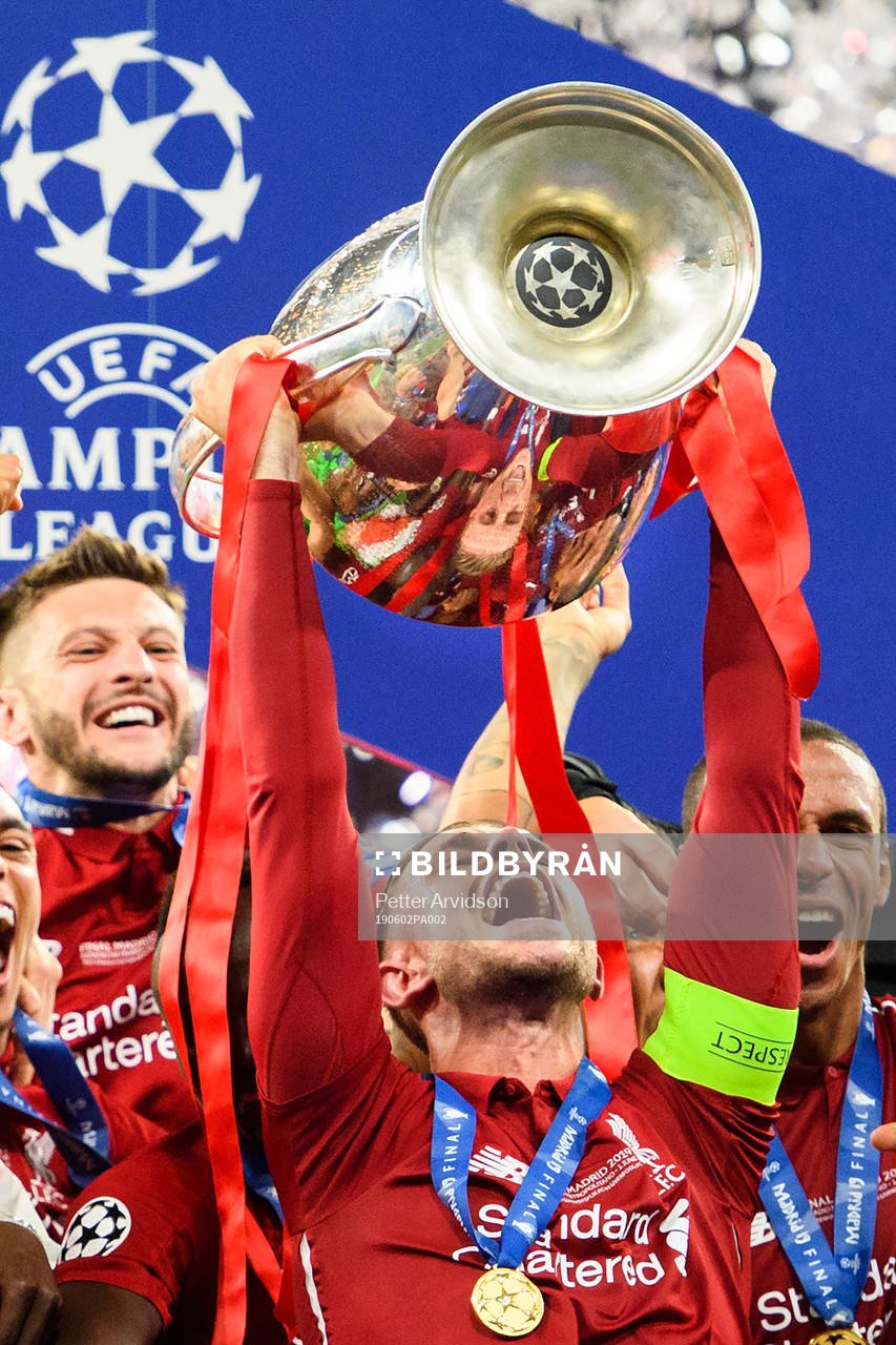 Jordan Henderson of Liverpool raises the throphy in front