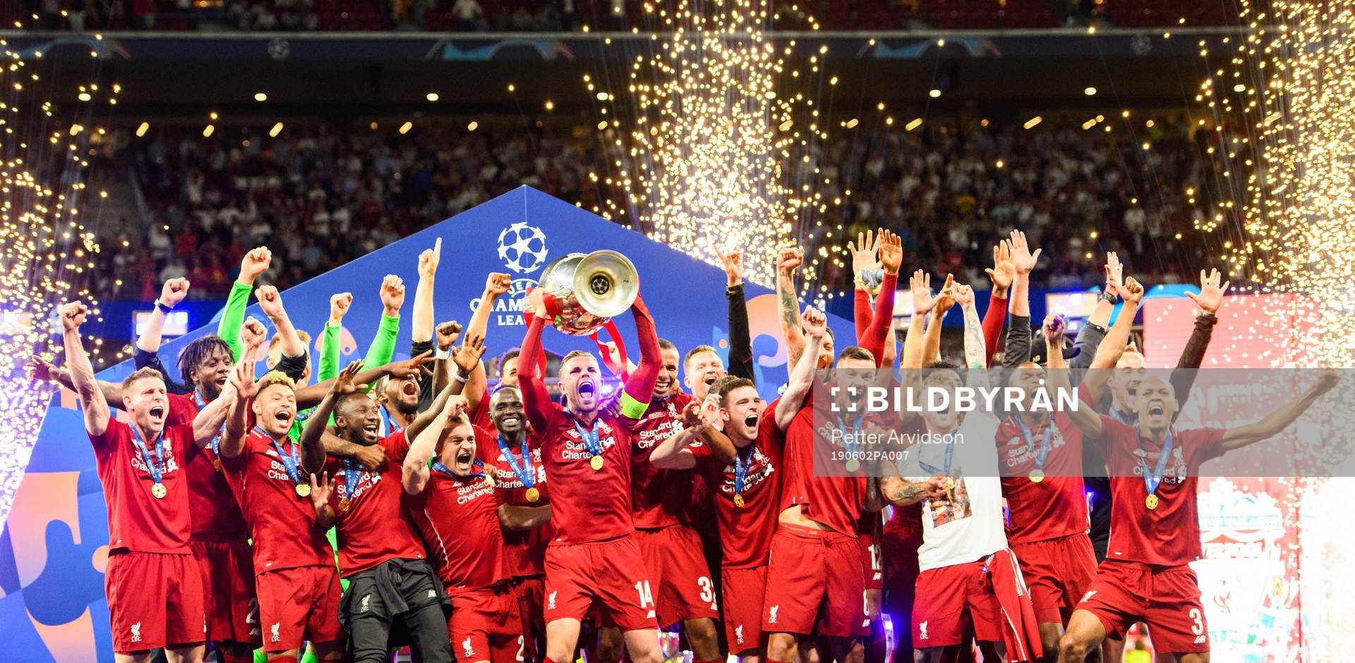 Jordan Henderson of Liverpool raises the throphy in front