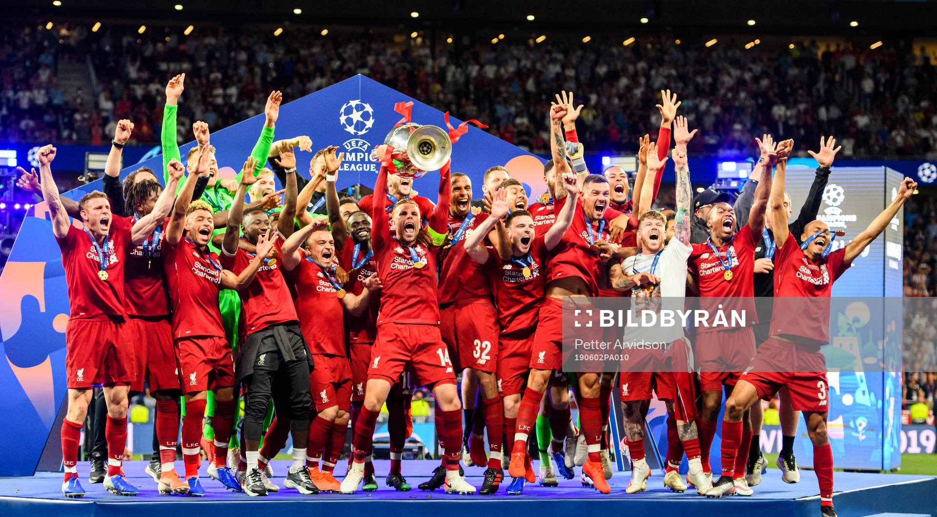 Jordan Henderson of Liverpool raises the throphy in front