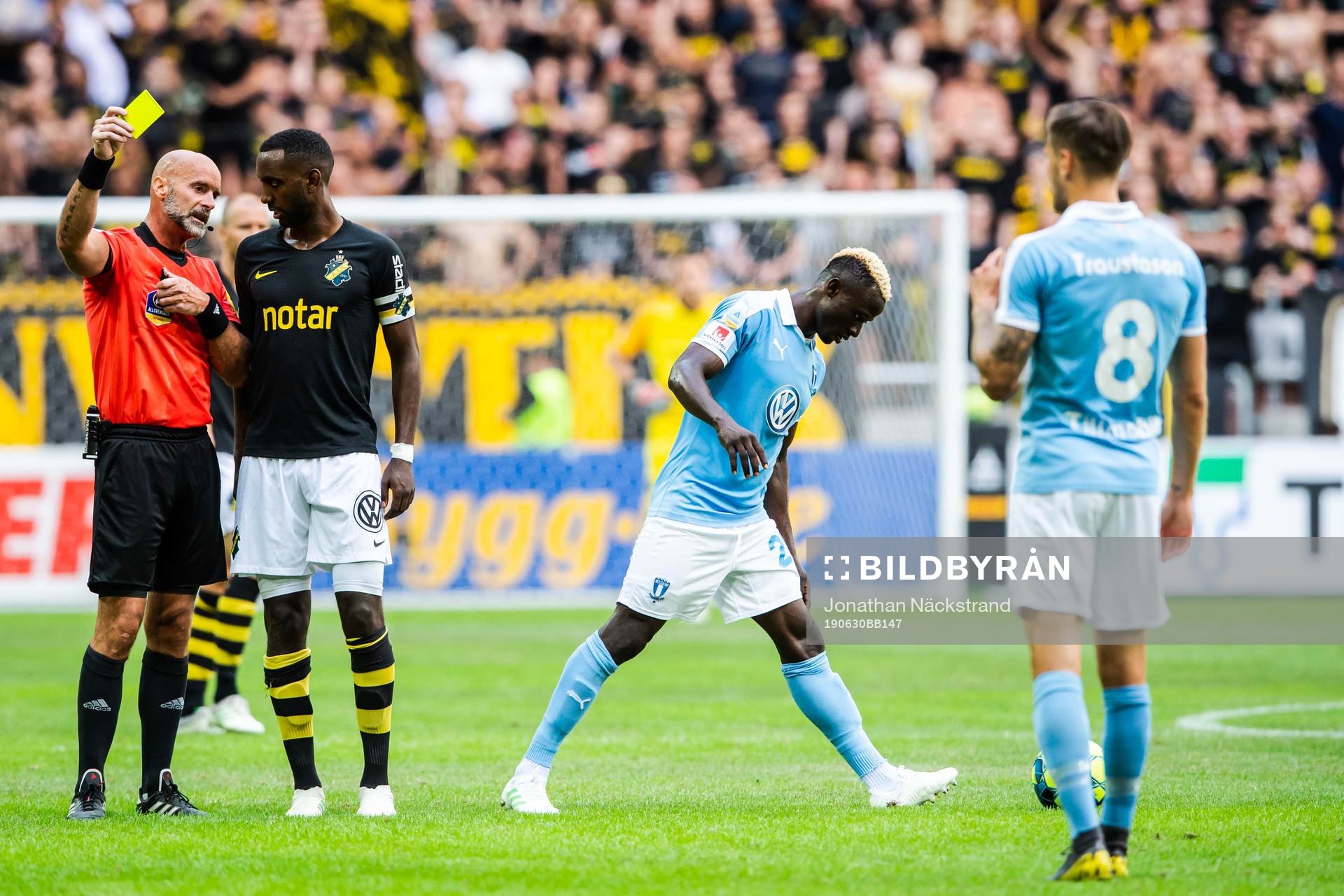 AIK:s Henok Goitom i samtal med domare Stefan Johannesson som tilldelar Malmö FFs Arnór Traustason en varning under fotbollsmatchen i Allsvenskan mellan AIK och Malmö FF den 30 juni 2019 i Stockholm.