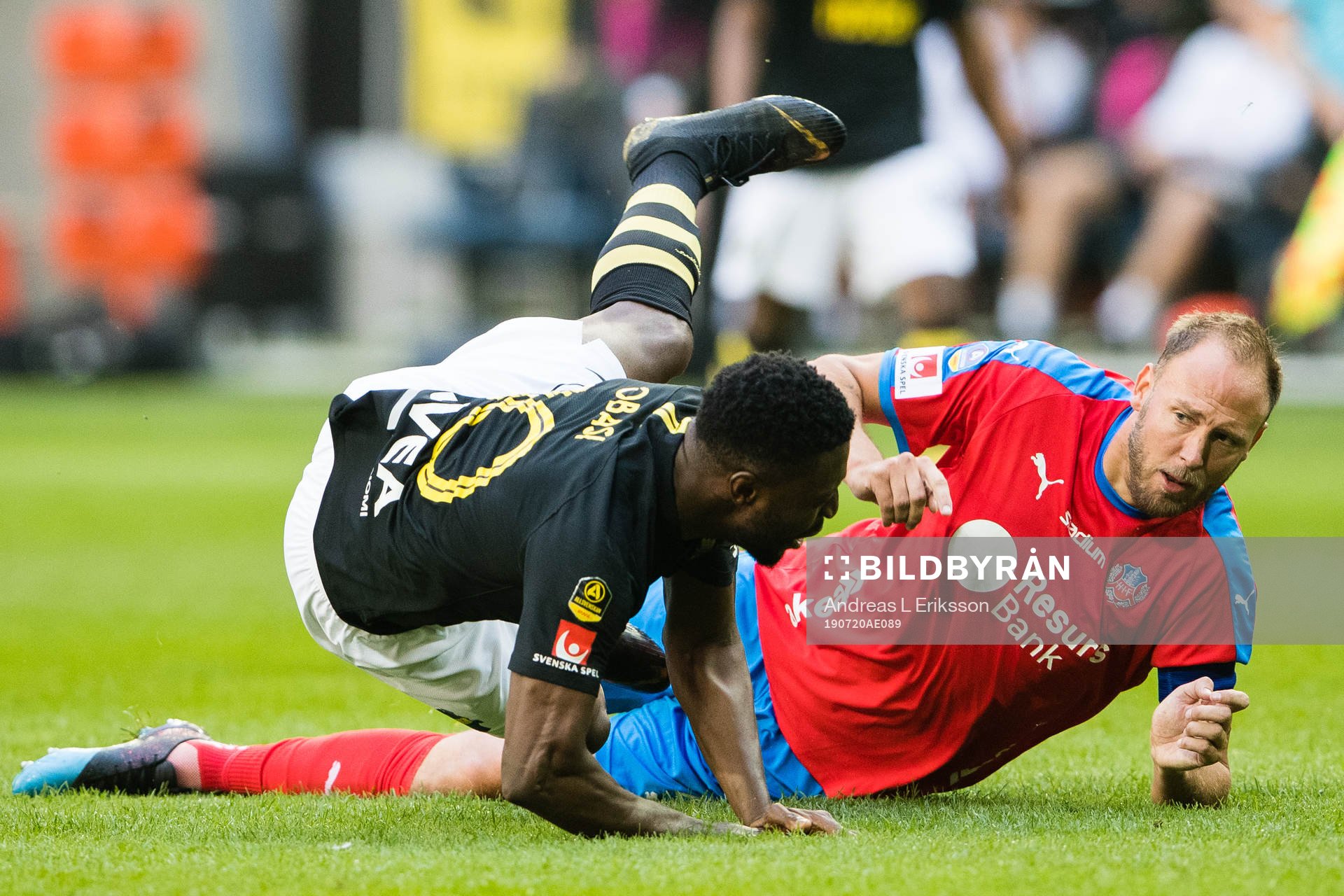 AIK:s Chinedu Obasi går omkull efter en närkamp med Helsingborgs Andreas Granqvist under fotbollsmatchen i Allsvenskan mellan AIK och Helsingborg den 20 juli 2019 i Stockholm.