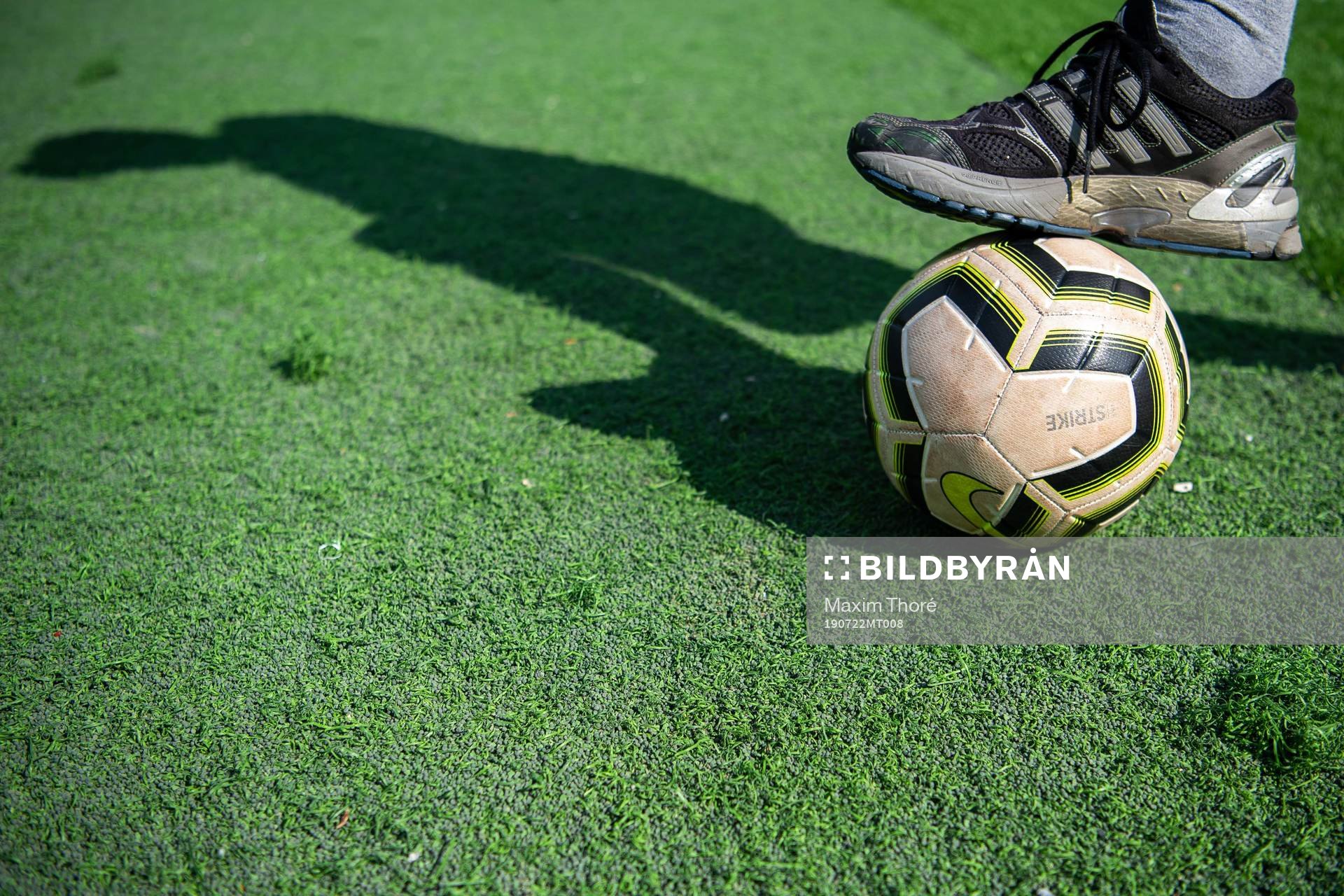 En person med en fotboll på konstgräs och gummigranulat