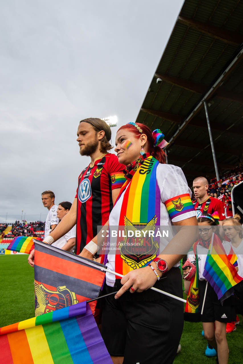 Östersunds Tom Pettersson under inmarschen med en maskot med en pridehallsduk under fotbollsmatchen i Allsvenskan mellan Östersund och Kalmar den 14 September 2019 i Östersund.
