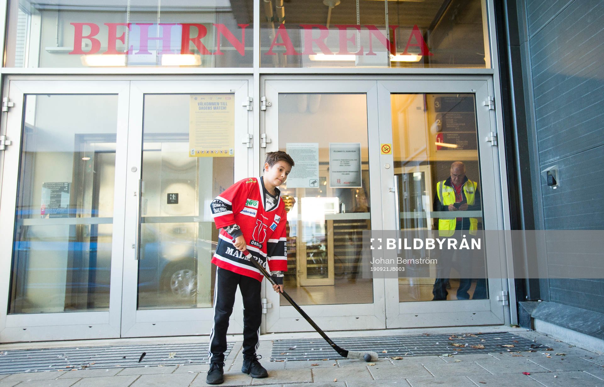 Kille med Örebrotröja och hockeyklubba utanför entrén