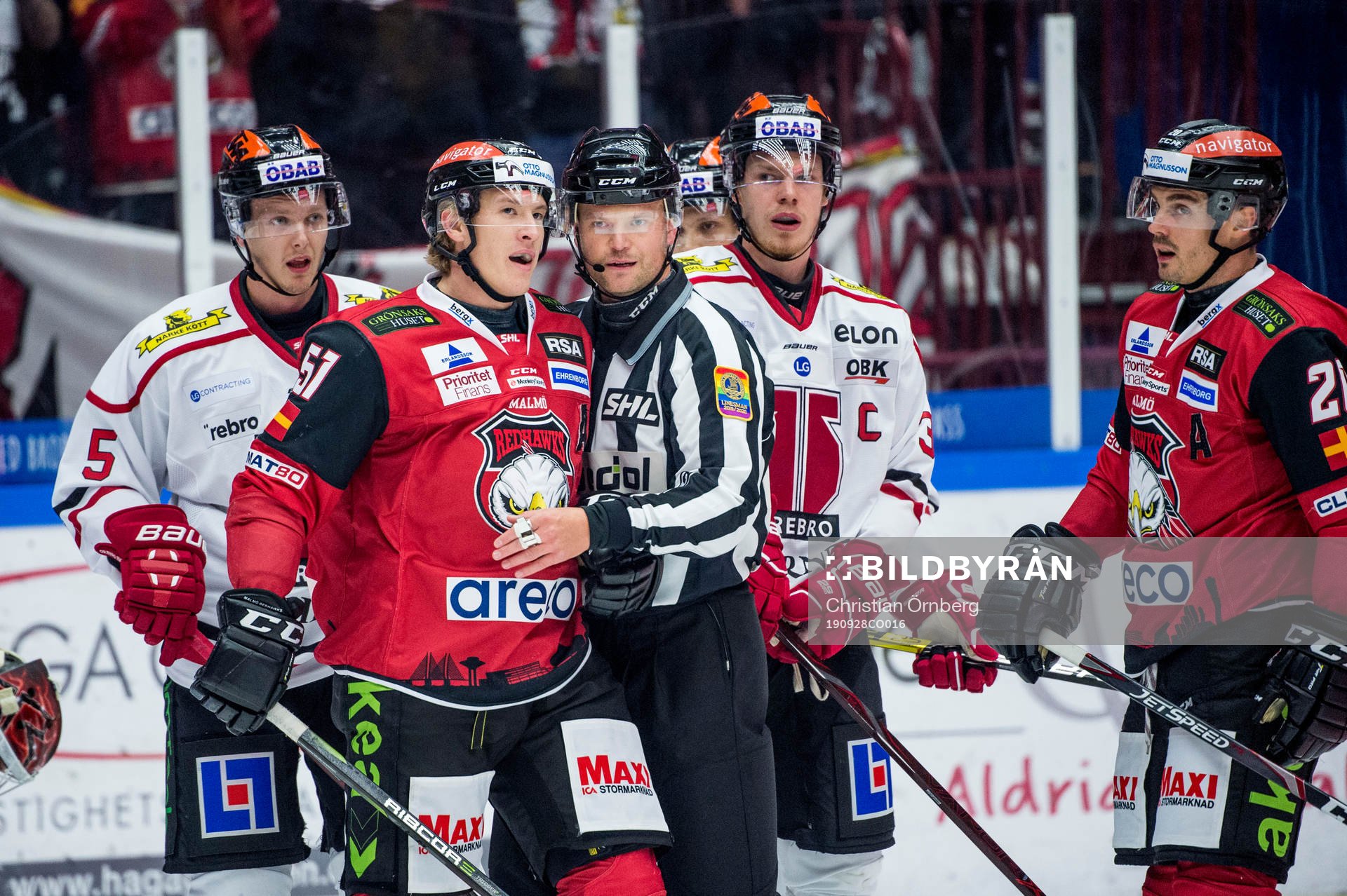 Domaren Ludvig Lundgren går emellan Malmö Redhawks Emil