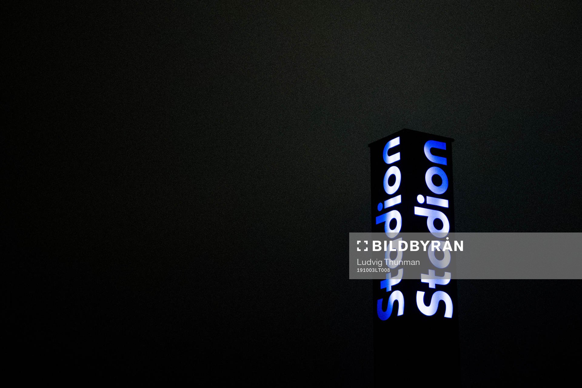 A sign lights up the dark sky with the logo for Stadion,