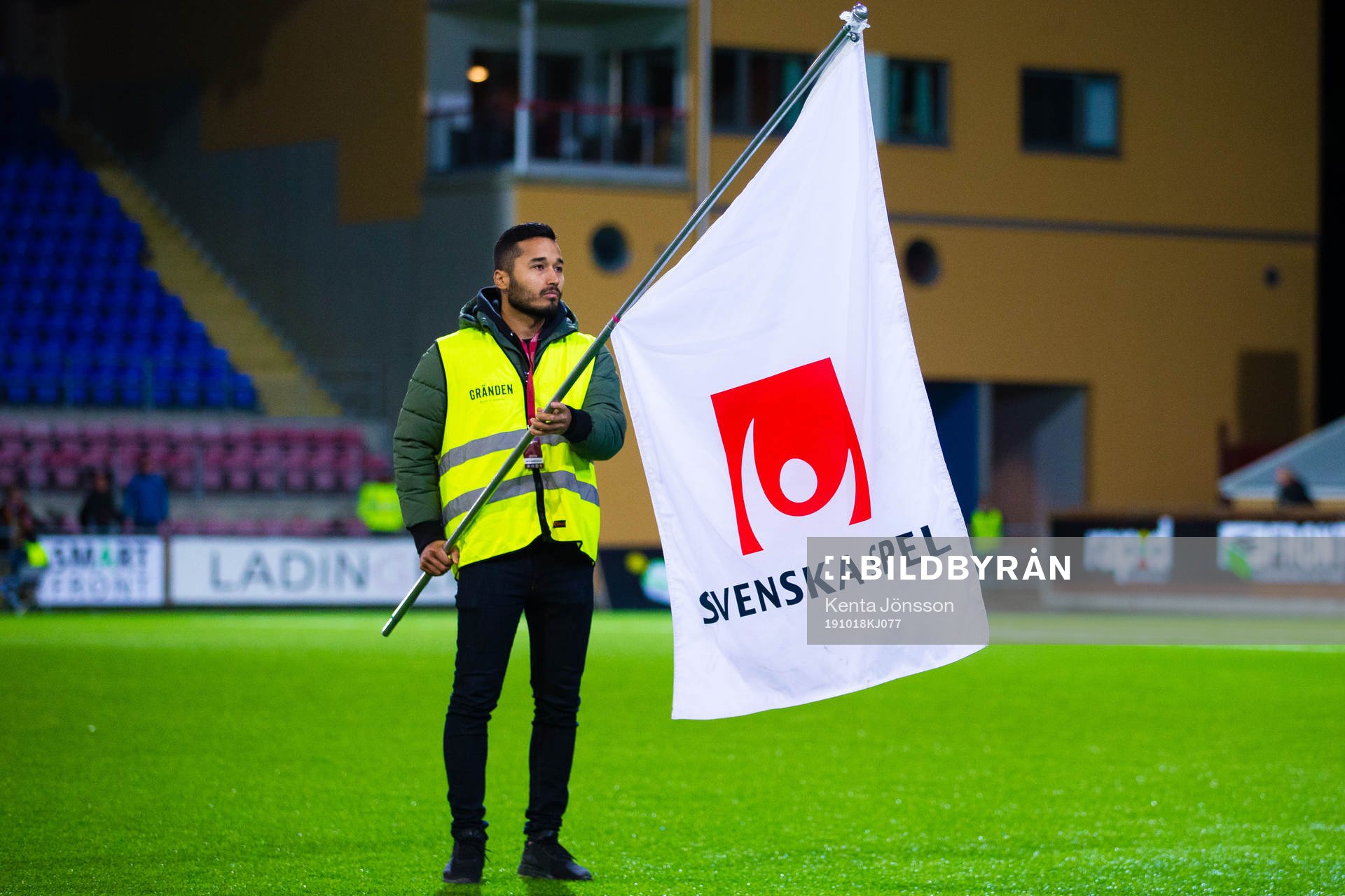 En fanbärare med en flagga med Svenska Spels logotyp