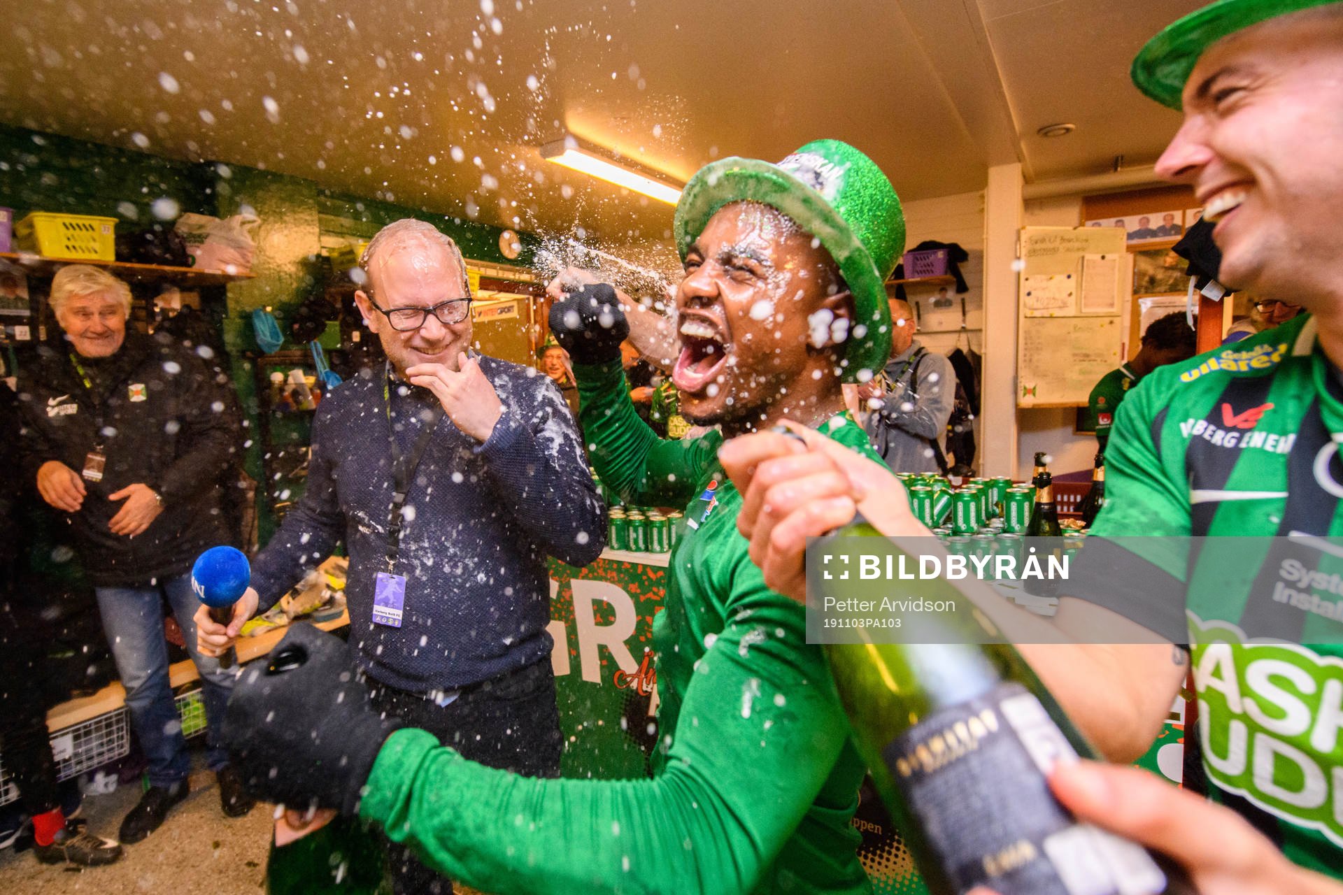 Hallands Nyheters reporter Simon Carlsson sprutas ner med champagne av Varbergs Nahom Girmai Netabay och Sebastian Möller i omklädningsrummet efter att Varbergs avancemang till Allsvenskan 2020 efter fotbollsmatchen i Superettan mellan Varberg och Mjällby den 3 november 2019 i Varberg.