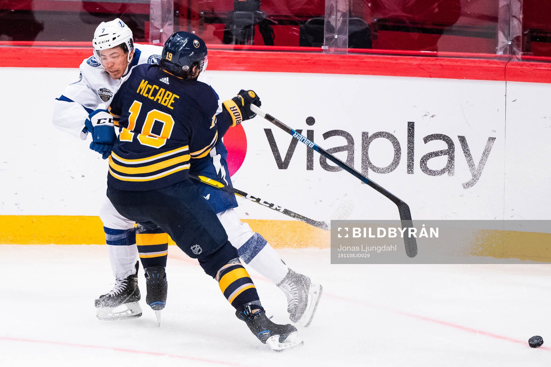 Jake McCabe of Buffalo Sabres tackles Mathieu Joseph of
