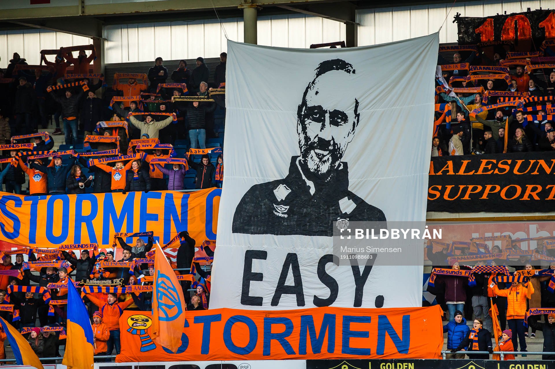 Spectators in the stands with a tifo of Lars Bohinen, head